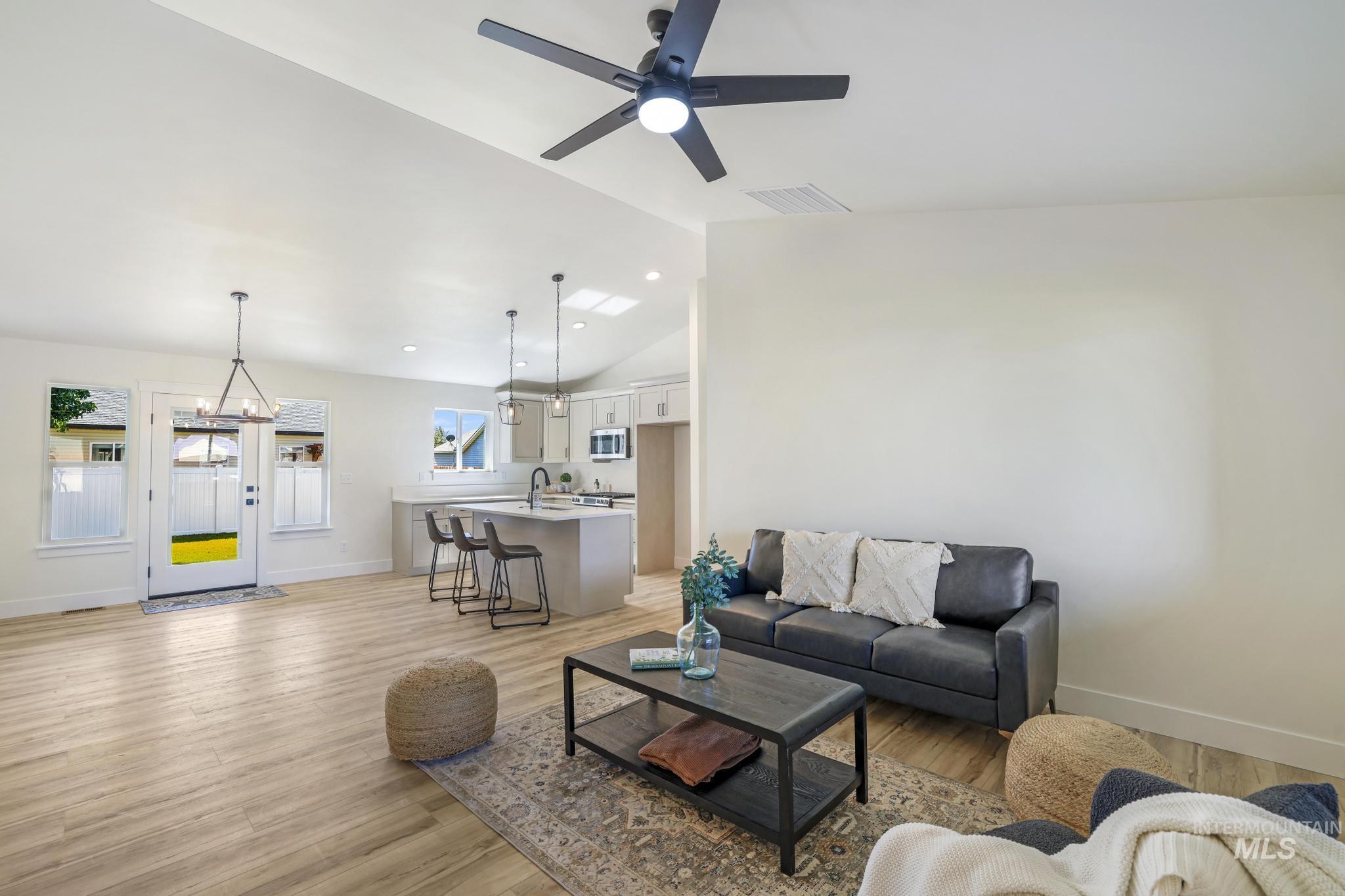 Living area featuring light wood-style floors, ceiling fan, and high vaulted ceiling