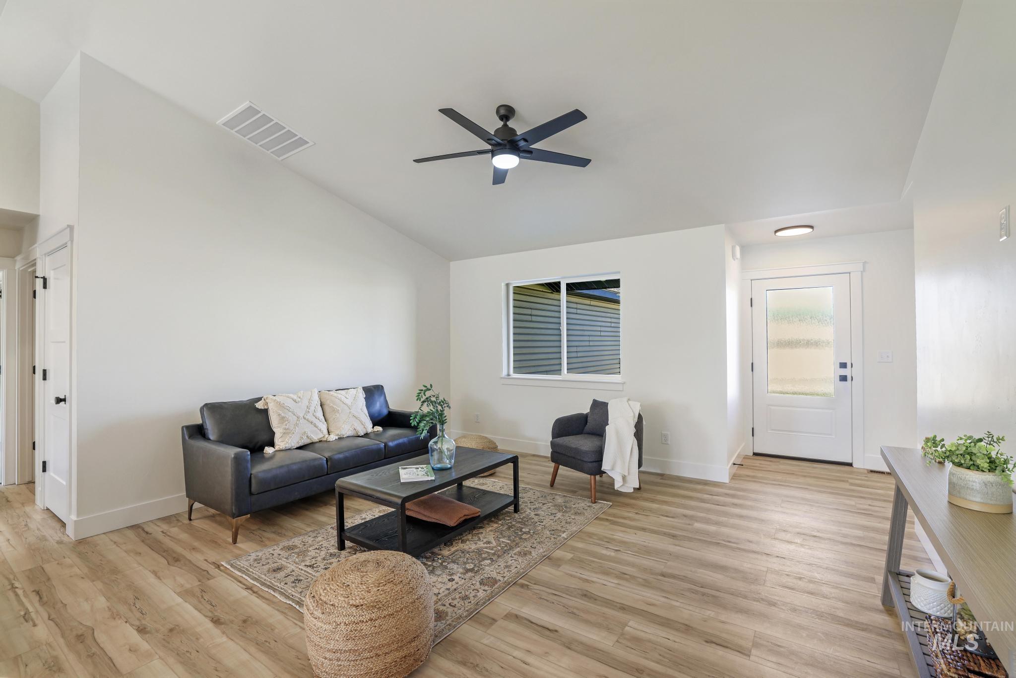 Living room featuring vaulted ceiling, light wood-type flooring, and a ceiling fan