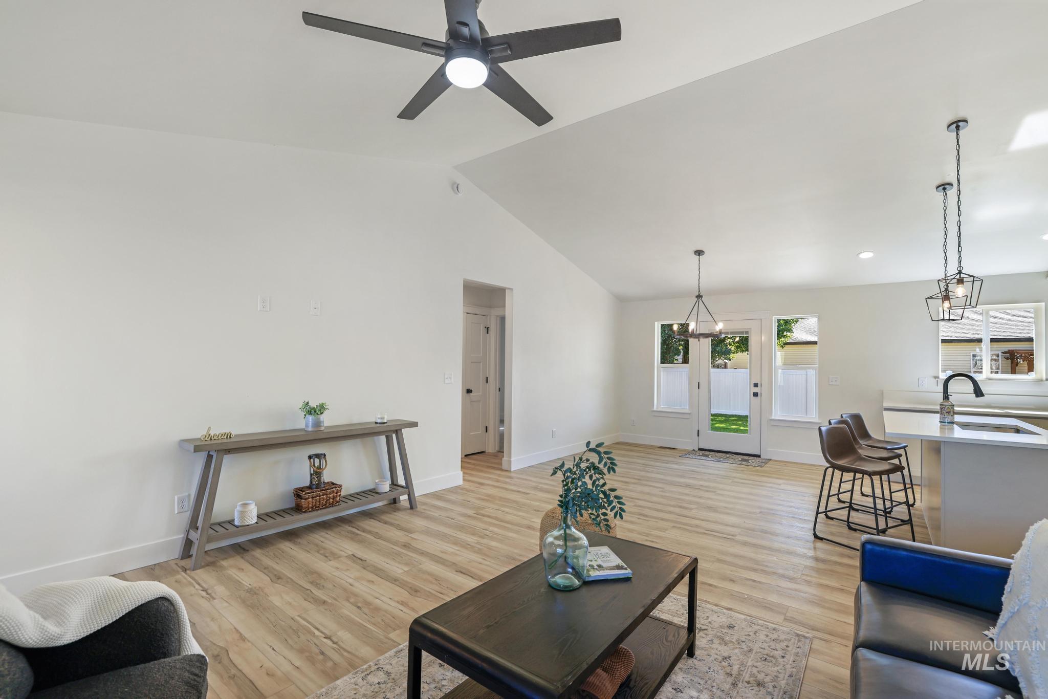 Living area with lofted ceiling, light wood-type flooring, ceiling fan, and a chandelier