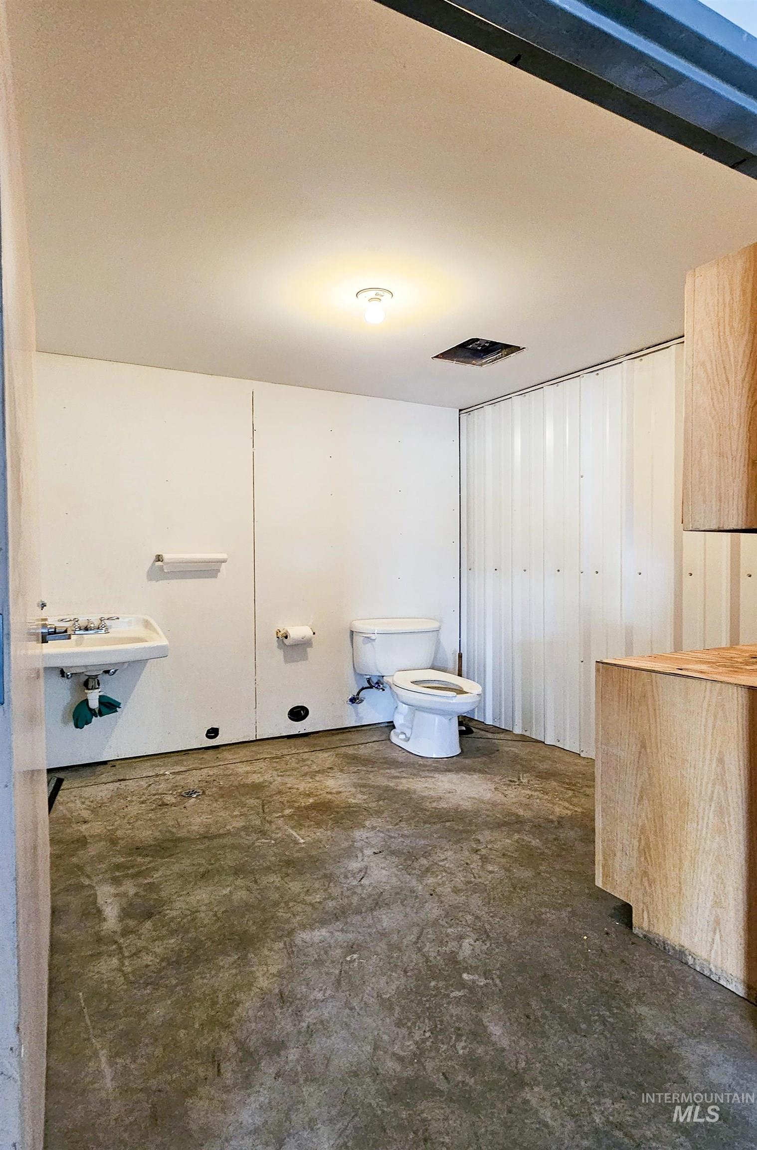 Bathroom featuring unfinished concrete floors and toilet