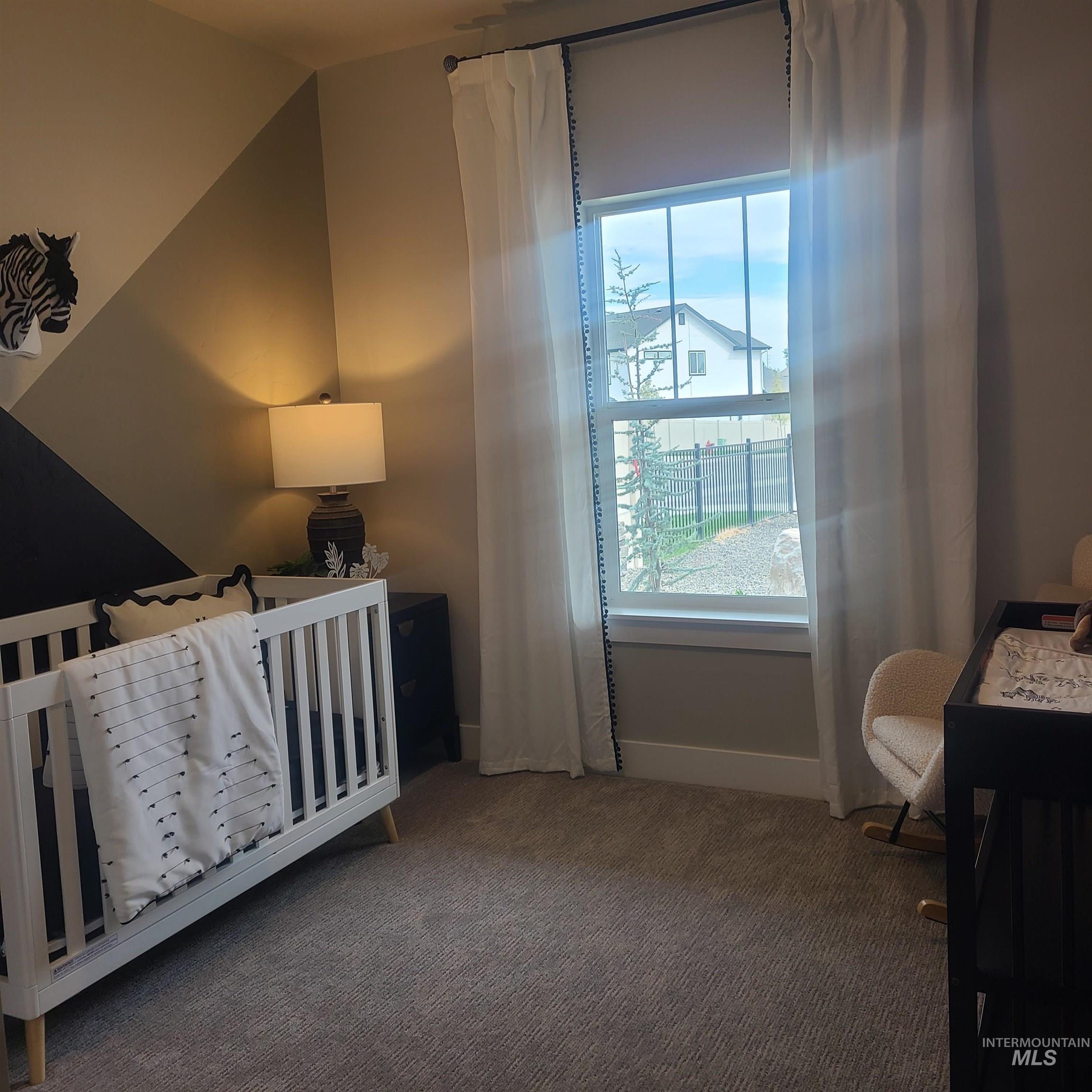 Carpeted bedroom with a nursery area and baseboards