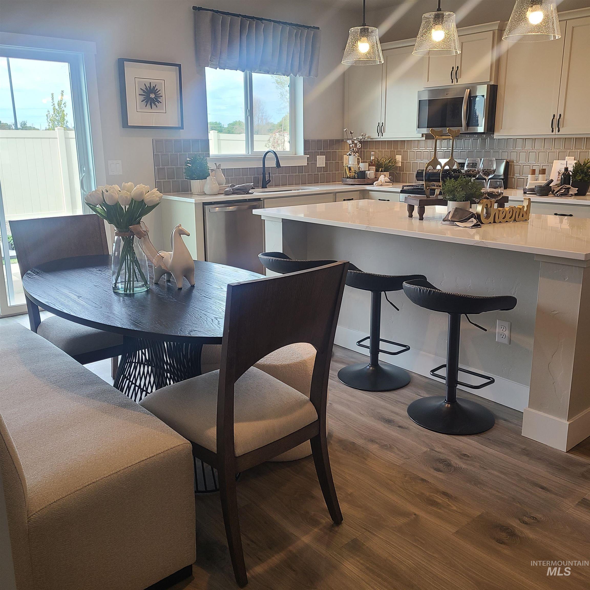 Kitchen with decorative backsplash, stainless steel appliances, dark wood-style flooring, and pendant lighting