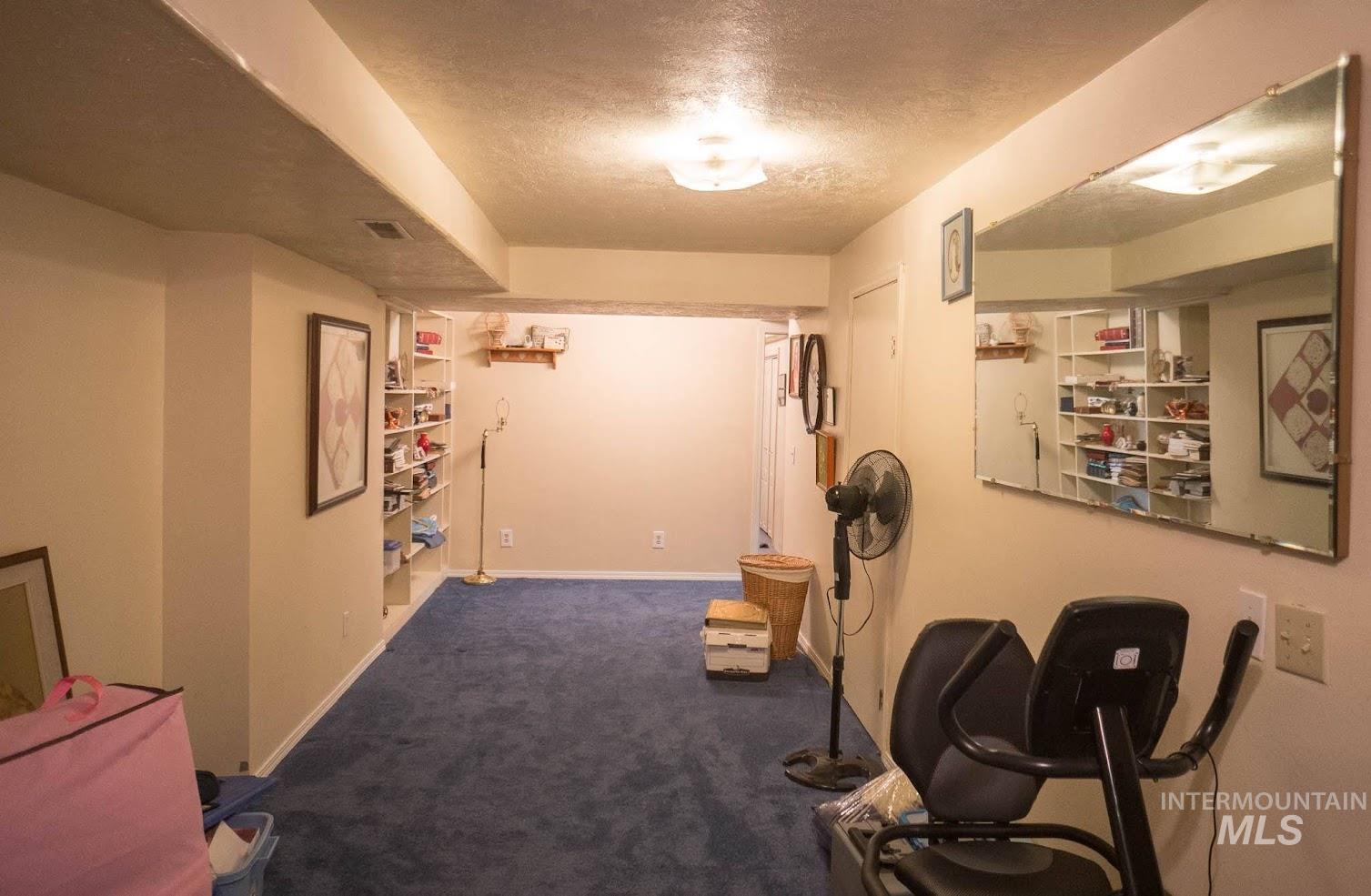 Exercise room featuring a textured ceiling and dark carpet