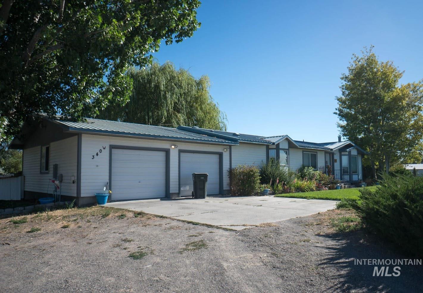 Ranch-style home with a metal roof, a garage, and concrete driveway