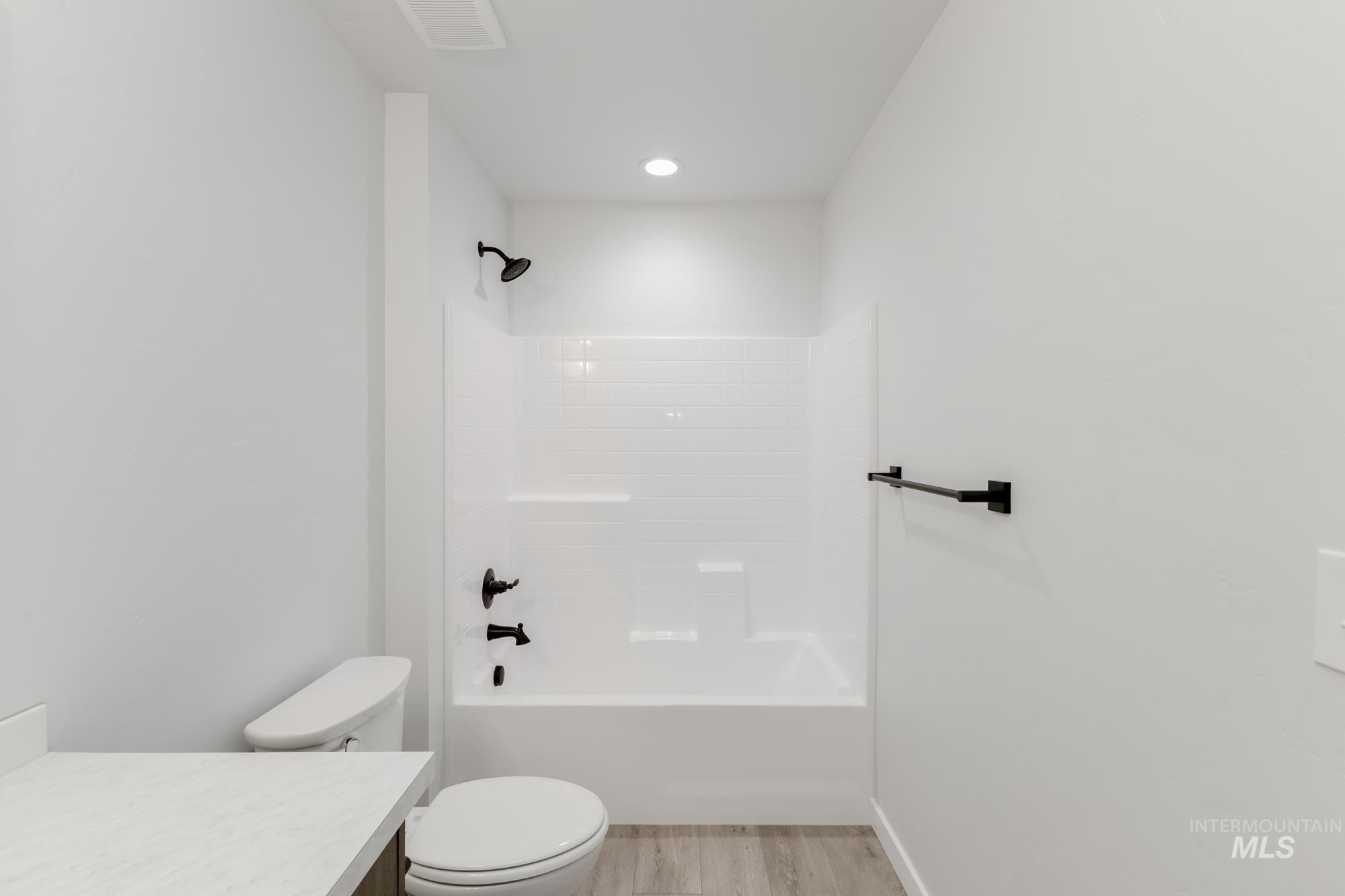 Bathroom featuring wood finished floors, vanity, bathing tub / shower combination, and recessed lighting