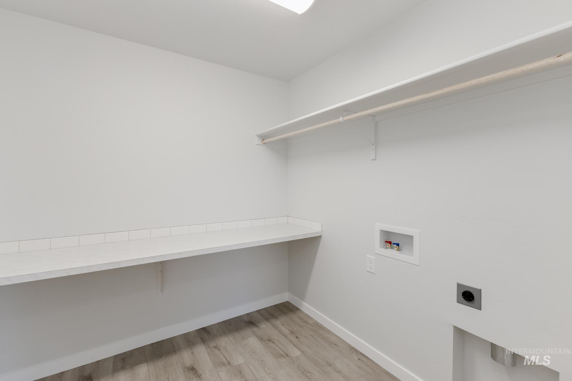 Laundry room featuring hookup for an electric dryer, light wood finished floors, and hookup for a washing machine