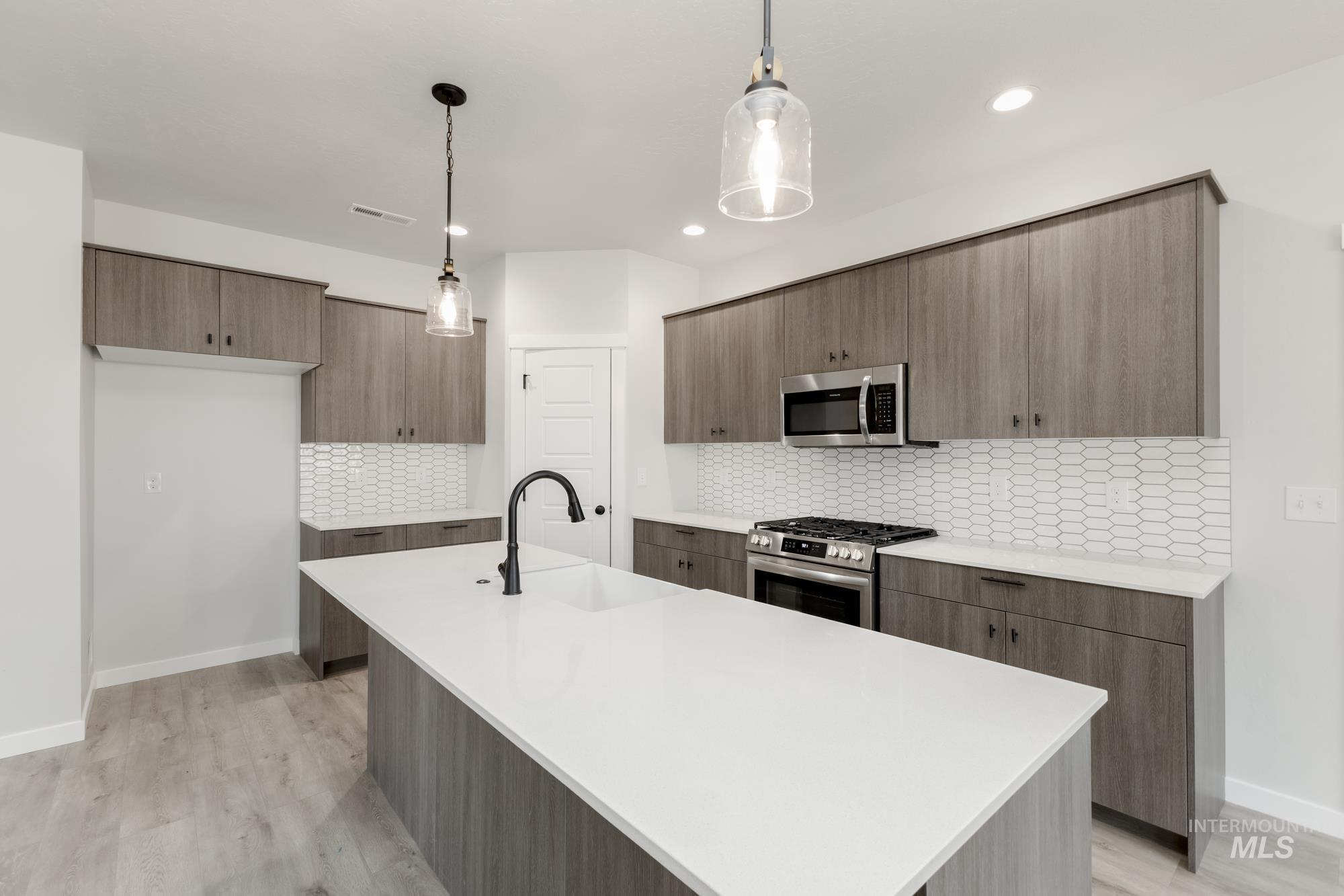 Kitchen featuring stainless steel appliances, modern cabinets, decorative backsplash, light countertops, and recessed lighting