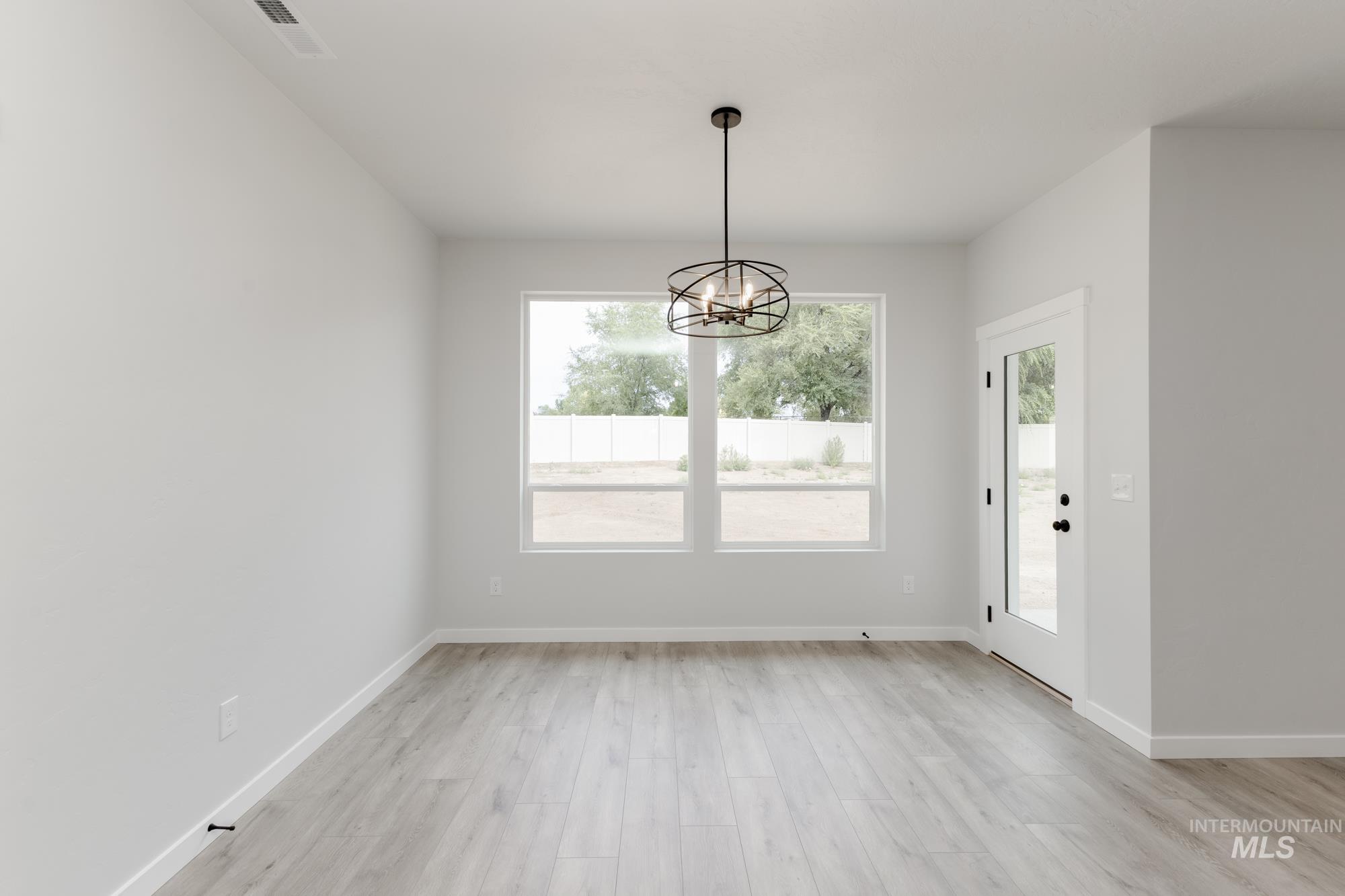 Unfurnished dining area featuring plenty of natural light, light wood-style floors, and a chandelier