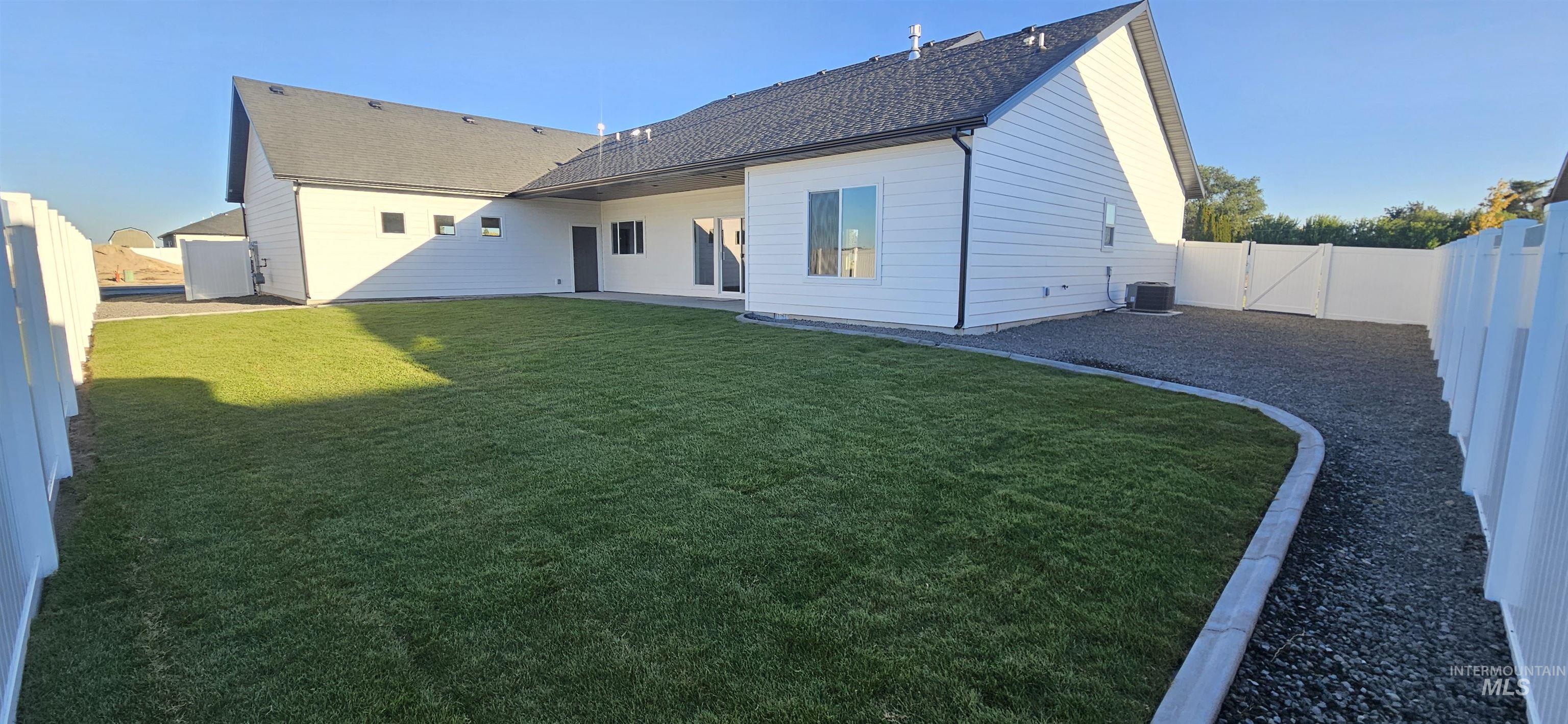 Back of house with a fenced backyard, a patio area, a shingled roof, and a gate