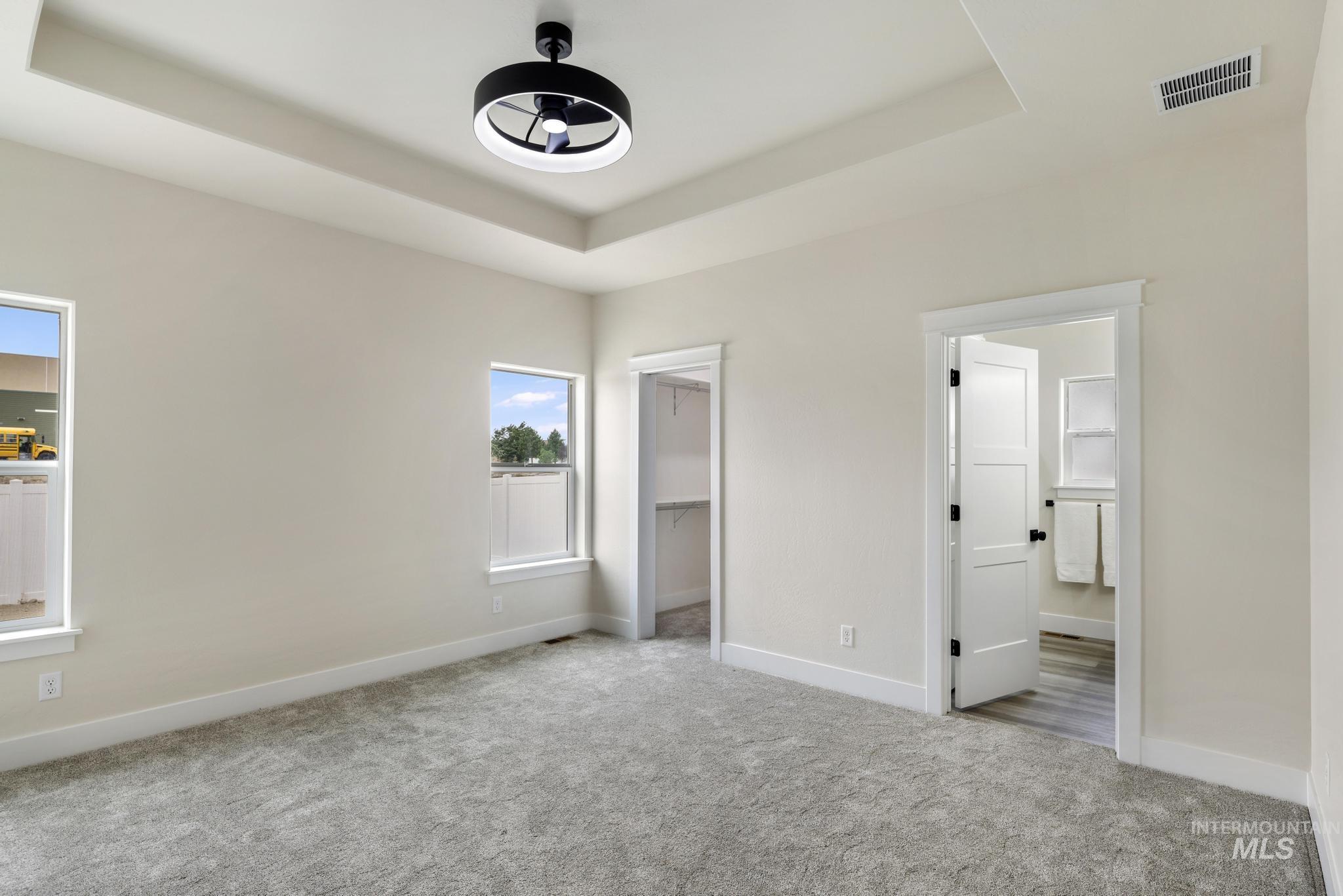 Unfurnished bedroom featuring a raised ceiling, carpet, and a walk in closet