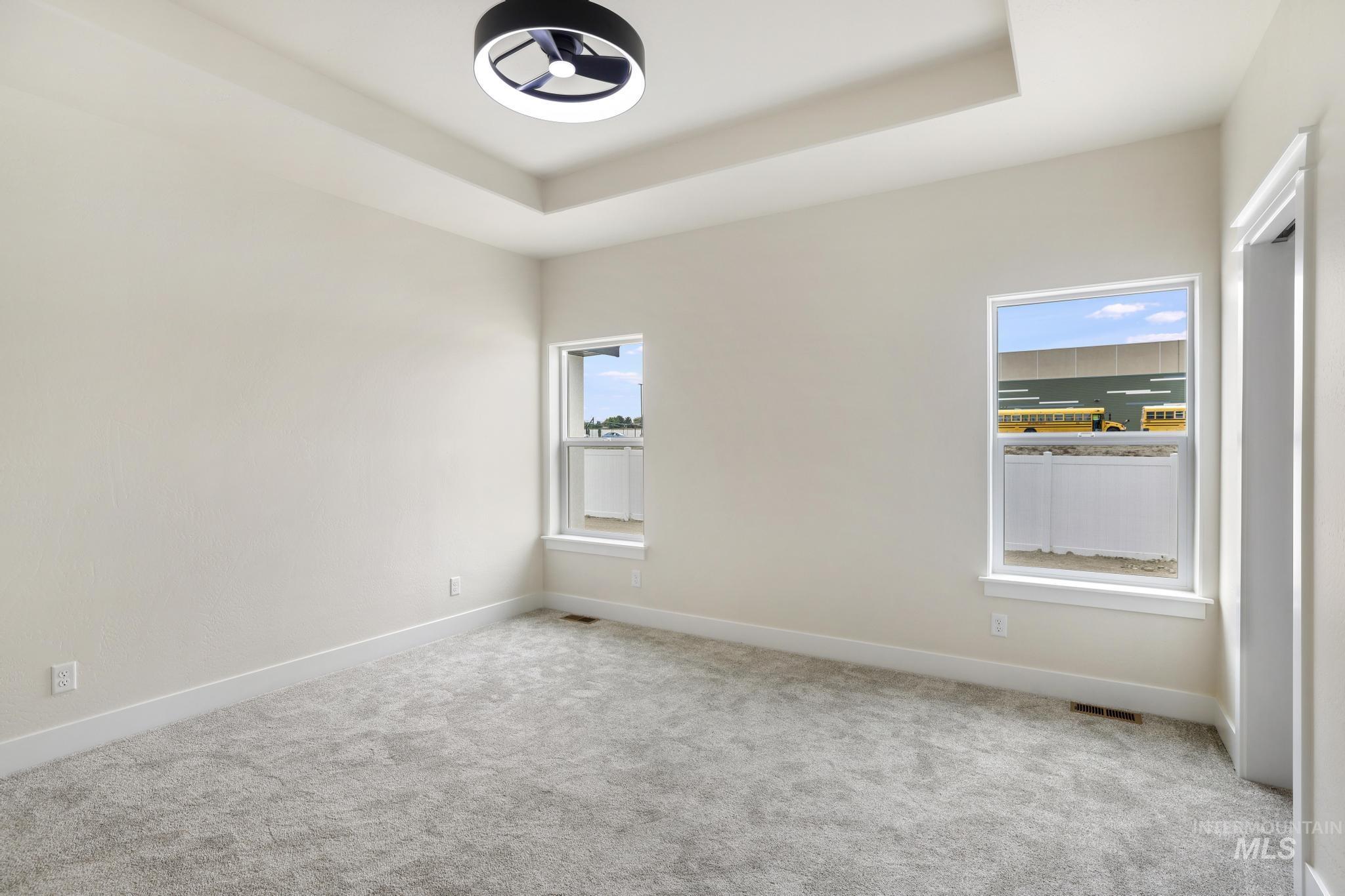 Carpeted empty room featuring a tray ceiling