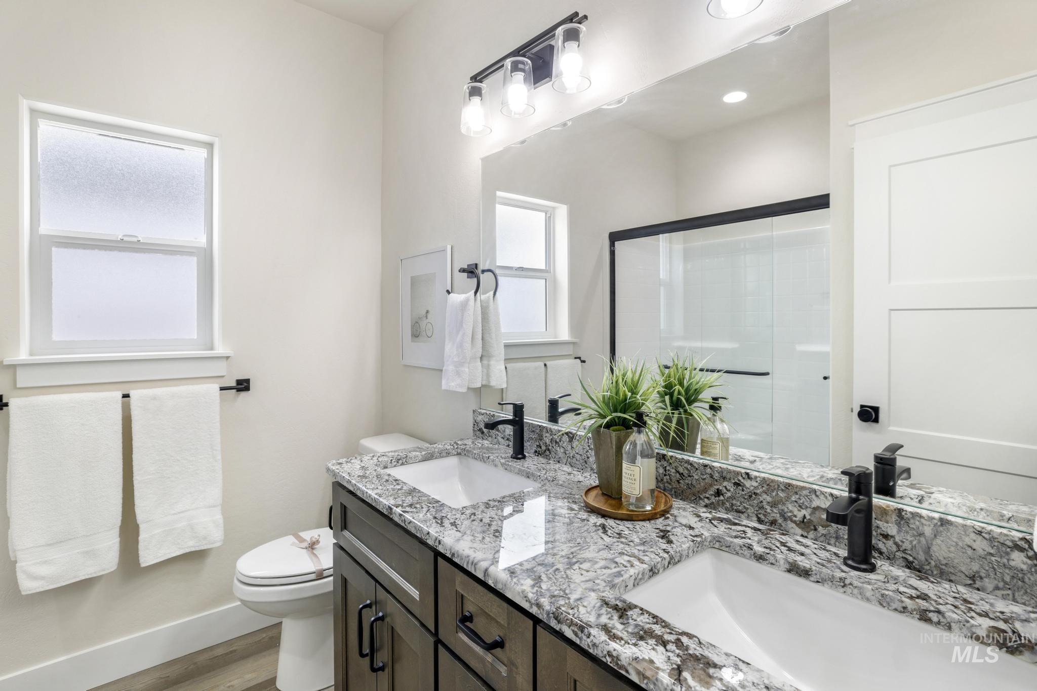 Full bathroom with a shower stall, double vanity, and light wood-style flooring