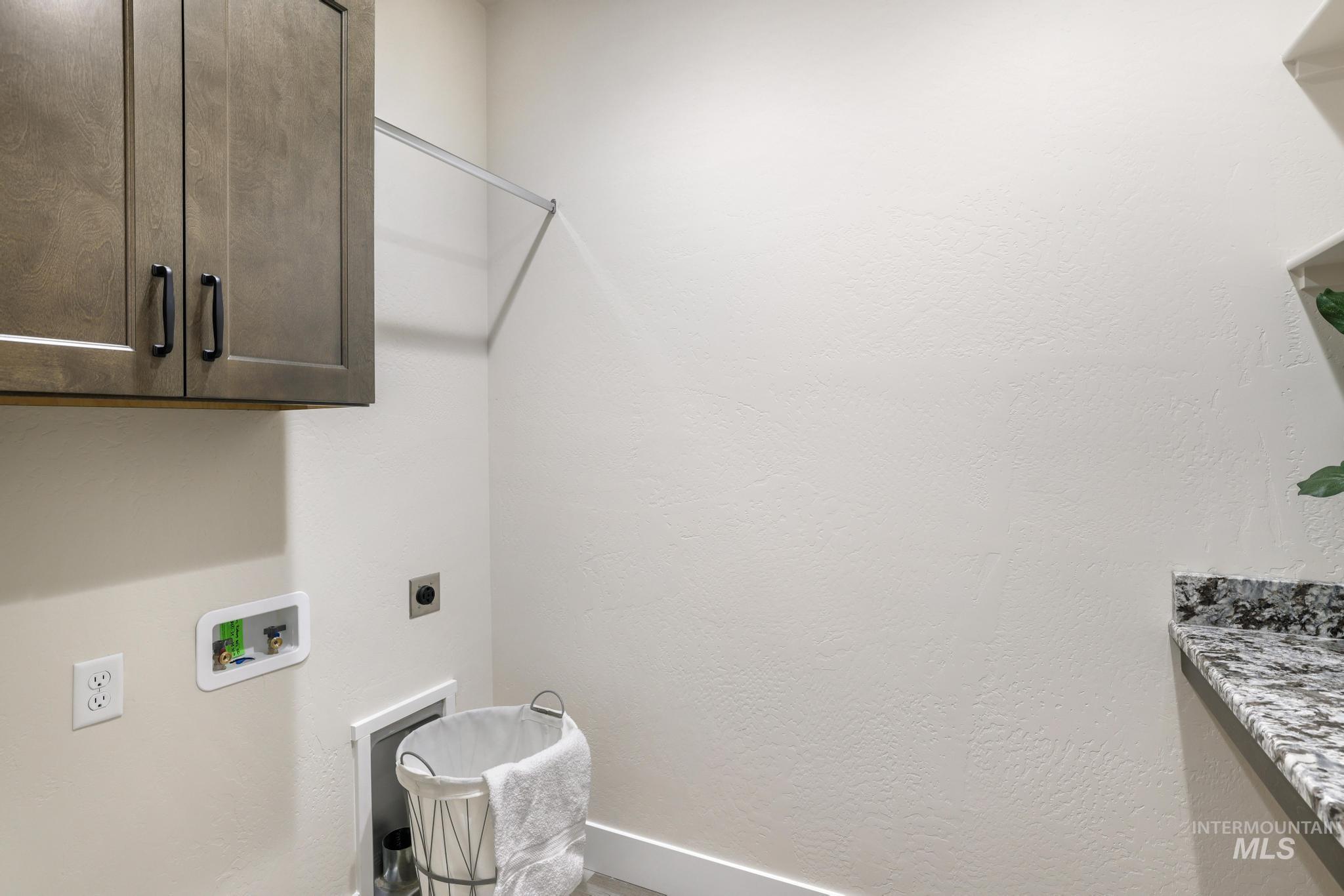 Washroom with cabinet space, washer hookup, hookup for an electric dryer, and a textured wall