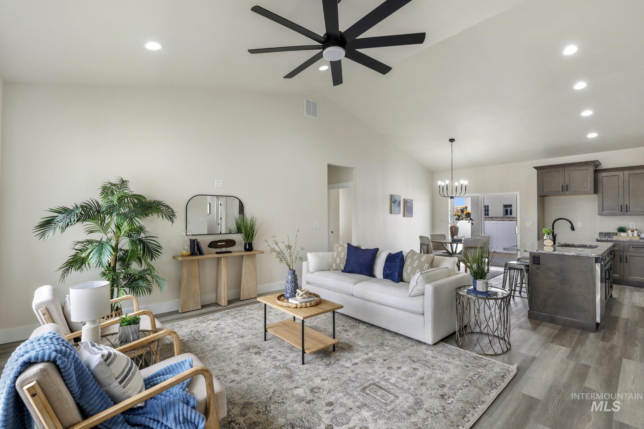 Living room featuring wood finished floors, recessed lighting, lofted ceiling, a chandelier, and ceiling fan