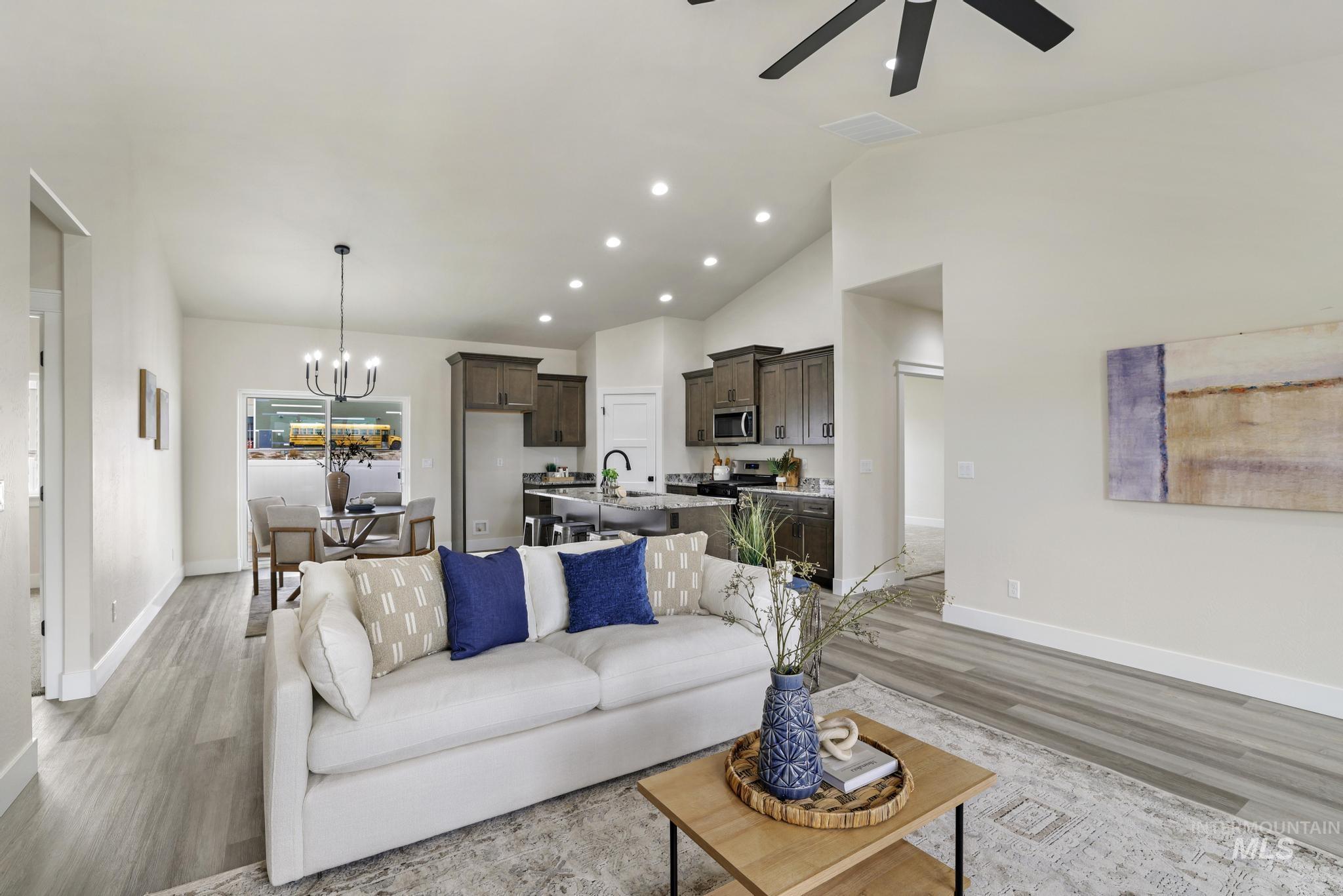 Living room with recessed lighting, light wood-style flooring, a chandelier, ceiling fan, and high vaulted ceiling