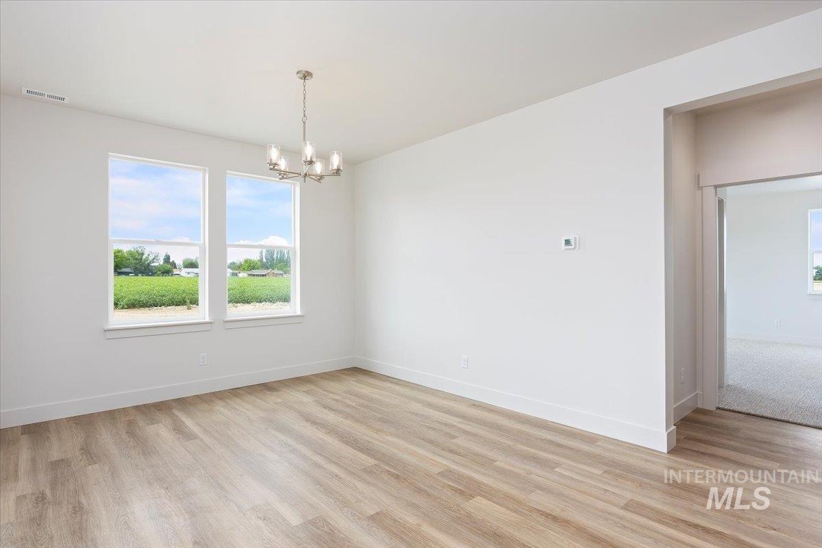 Unfurnished room featuring a chandelier and light wood-type flooring