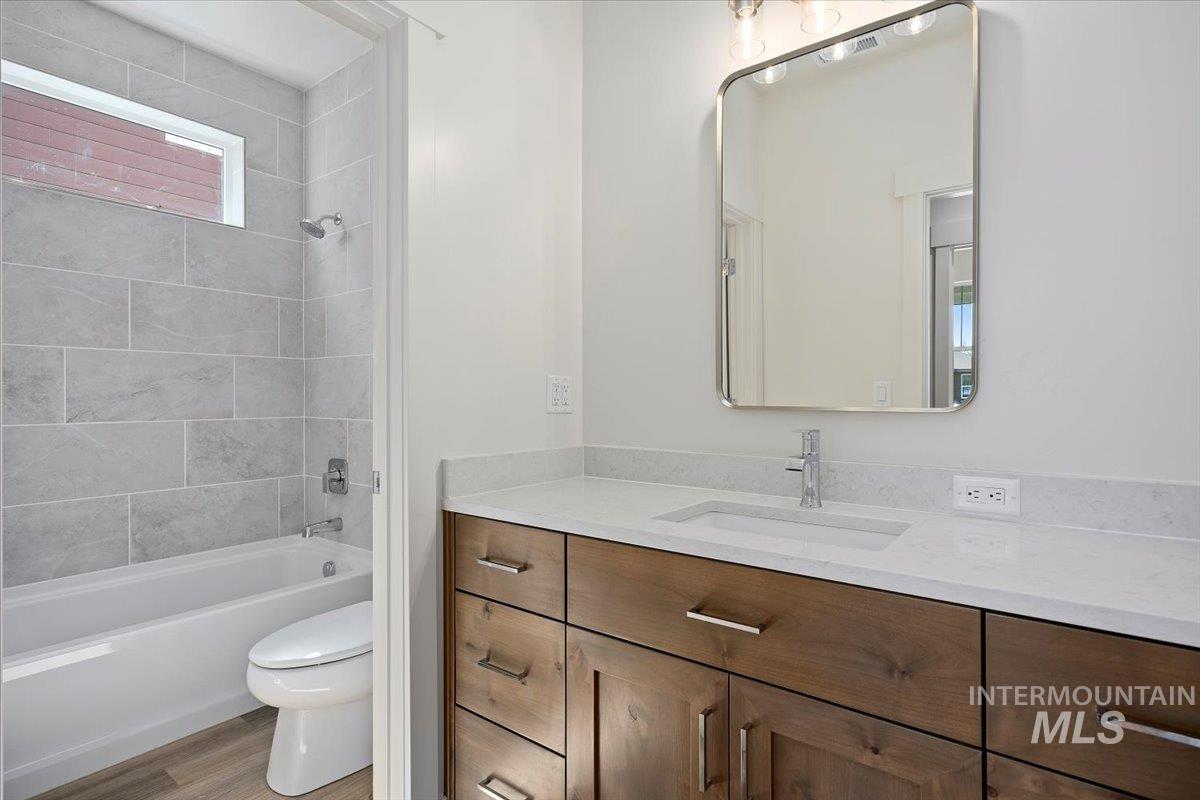 Bathroom with vanity, wood finished floors, and shower / washtub combination