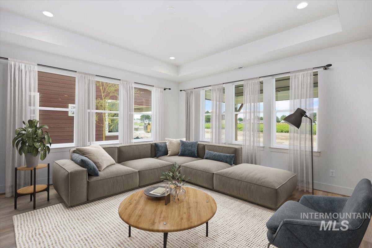 Living room with a tray ceiling, wood finished floors, and recessed lighting