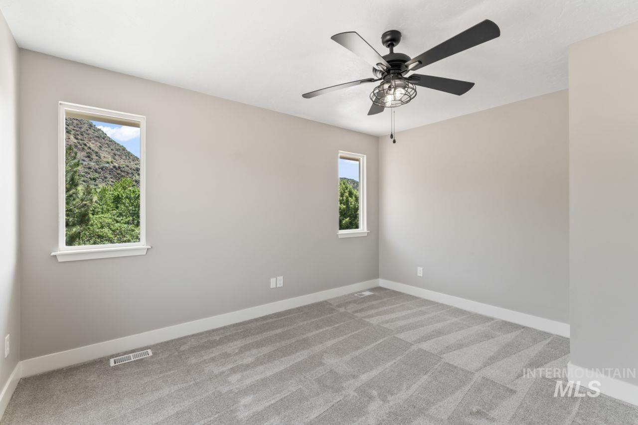 Unfurnished room with plenty of natural light, a ceiling fan, and carpet floors