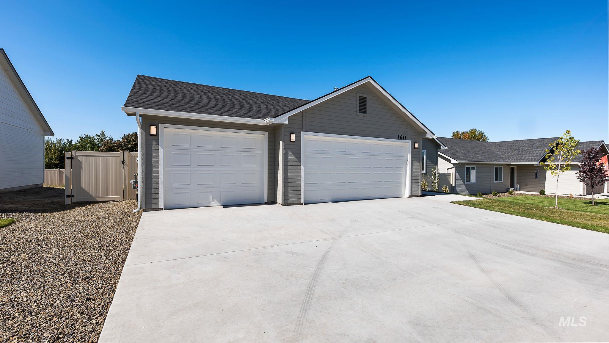 Ranch-style house featuring a shingled roof, concrete driveway, a garage, and a gate