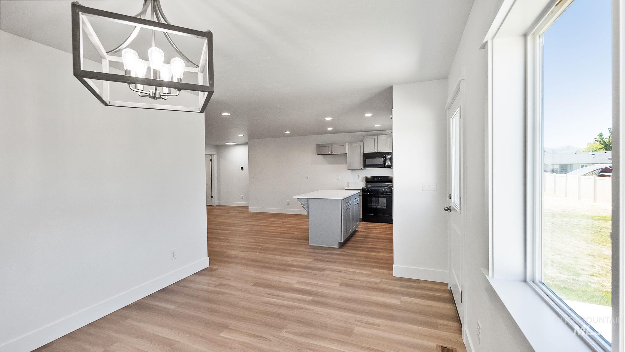 Kitchen with gray cabinets, light countertops, black appliances, light wood finished floors, and recessed lighting