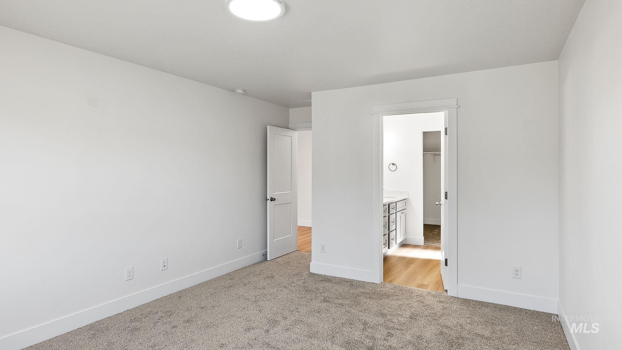 Unfurnished bedroom with light colored carpet and ensuite bath