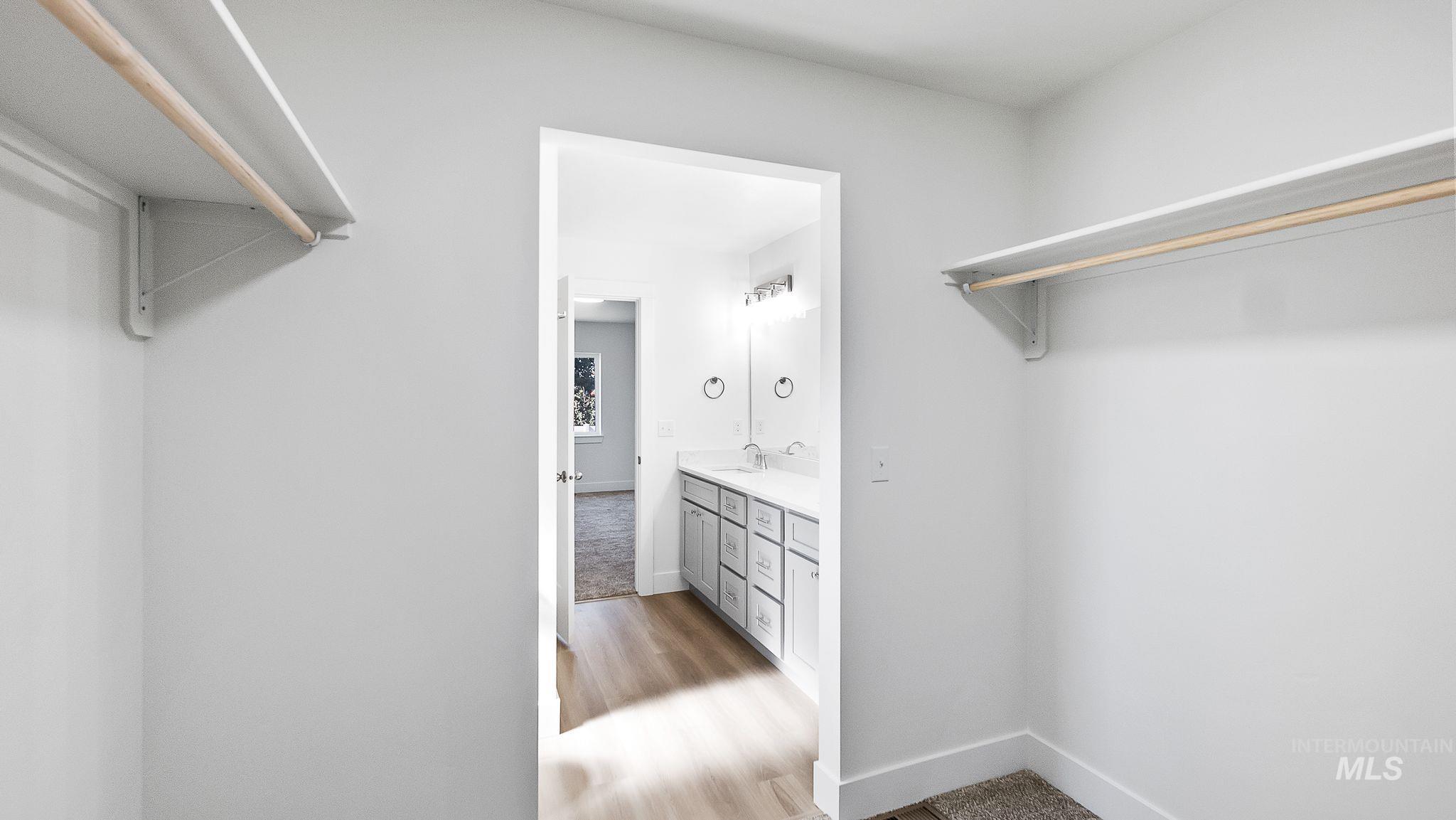 Spacious closet with light wood finished floors and a sink