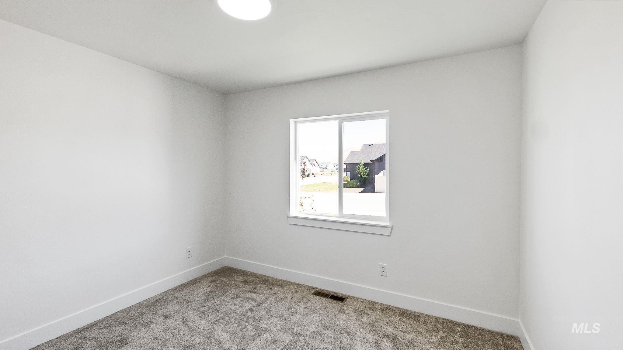 Carpeted spare room featuring baseboards
