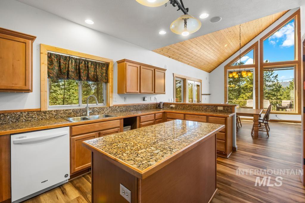 Kitchen with white dishwasher, pendant lighting, a peninsula, tile counters, and brown cabinetry