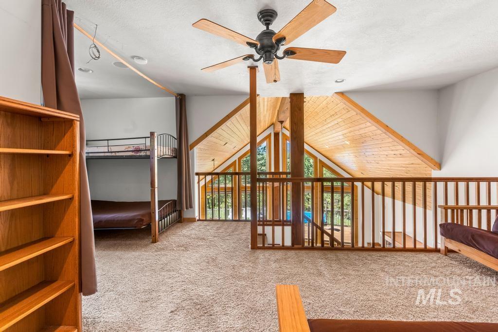 Unfurnished bedroom with light carpet, vaulted ceiling, and a ceiling fan