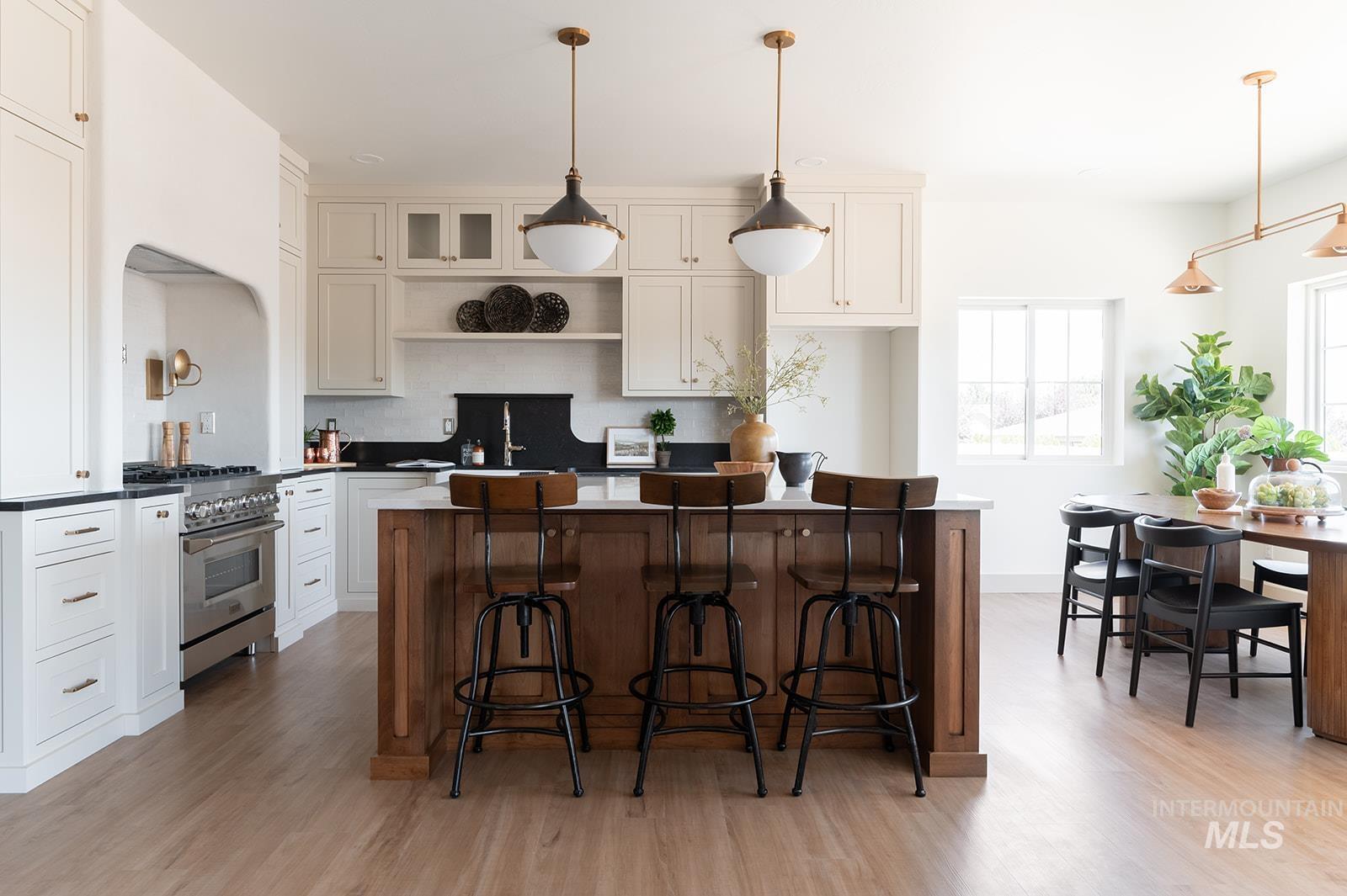 Kitchen featuring high end stainless steel range, open shelves, light wood-type flooring, decorative backsplash, and a kitchen island