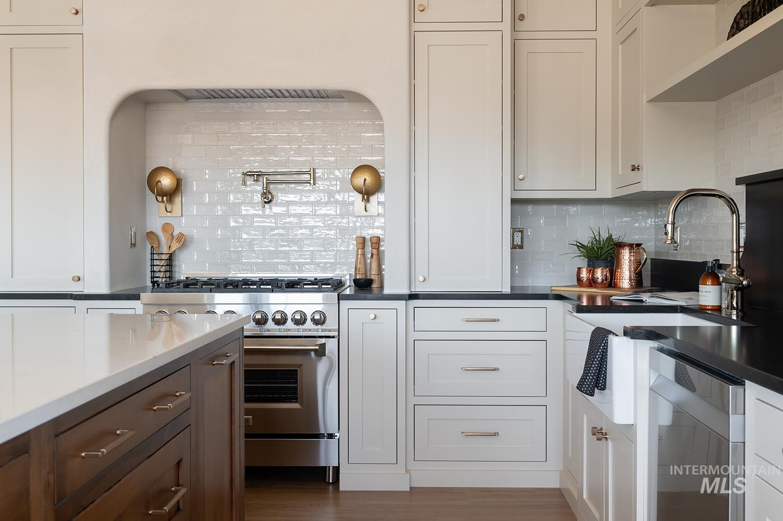 Kitchen with tasteful backsplash, stainless steel appliances, dark countertops, dark wood-style flooring, and white cabinets