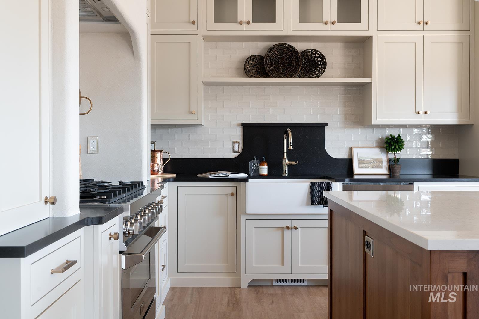 Kitchen featuring open shelves, high end stove, backsplash, and white cabinetry