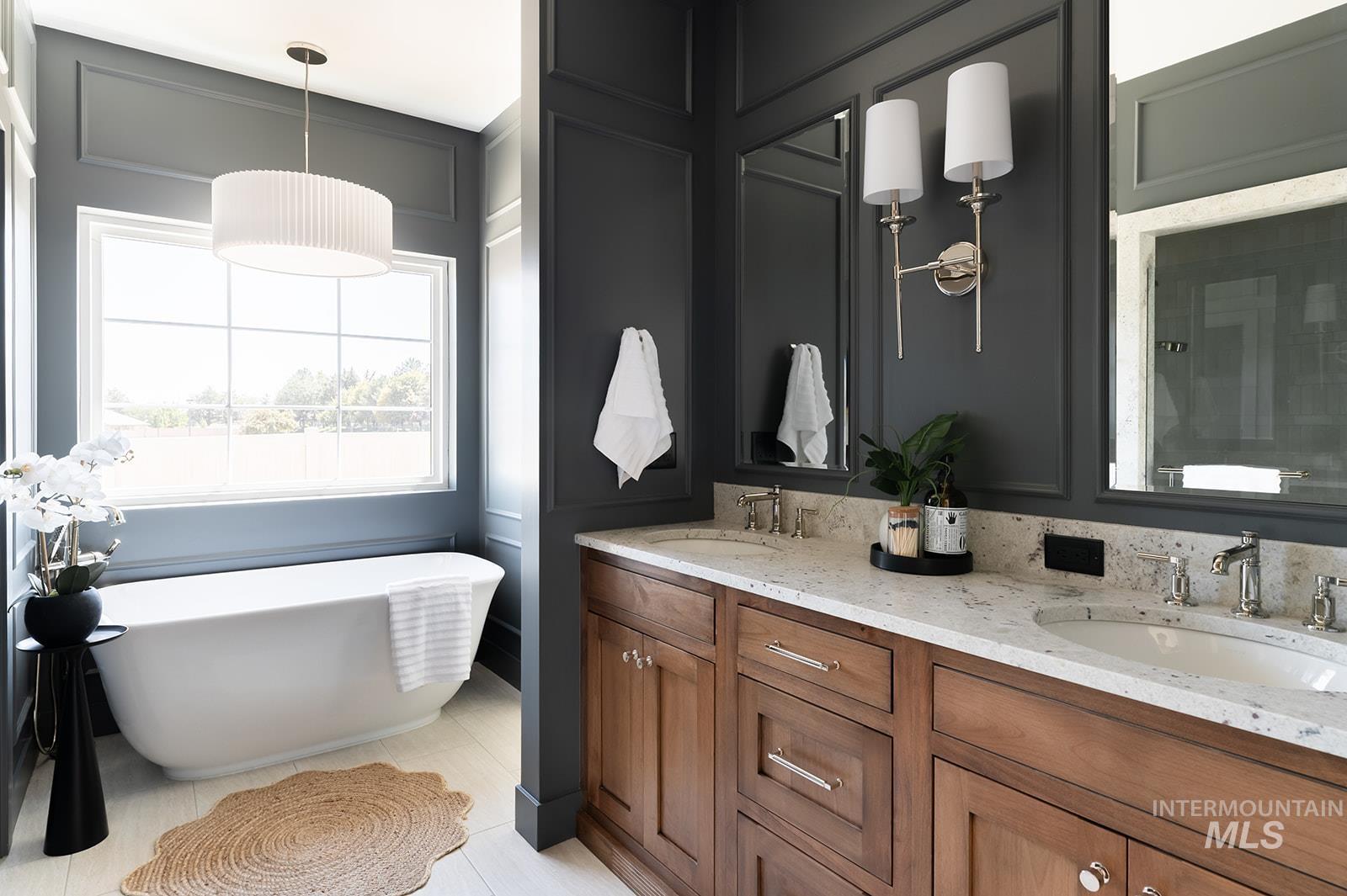 Full bath featuring double vanity, a soaking tub, a decorative wall, and tile patterned flooring