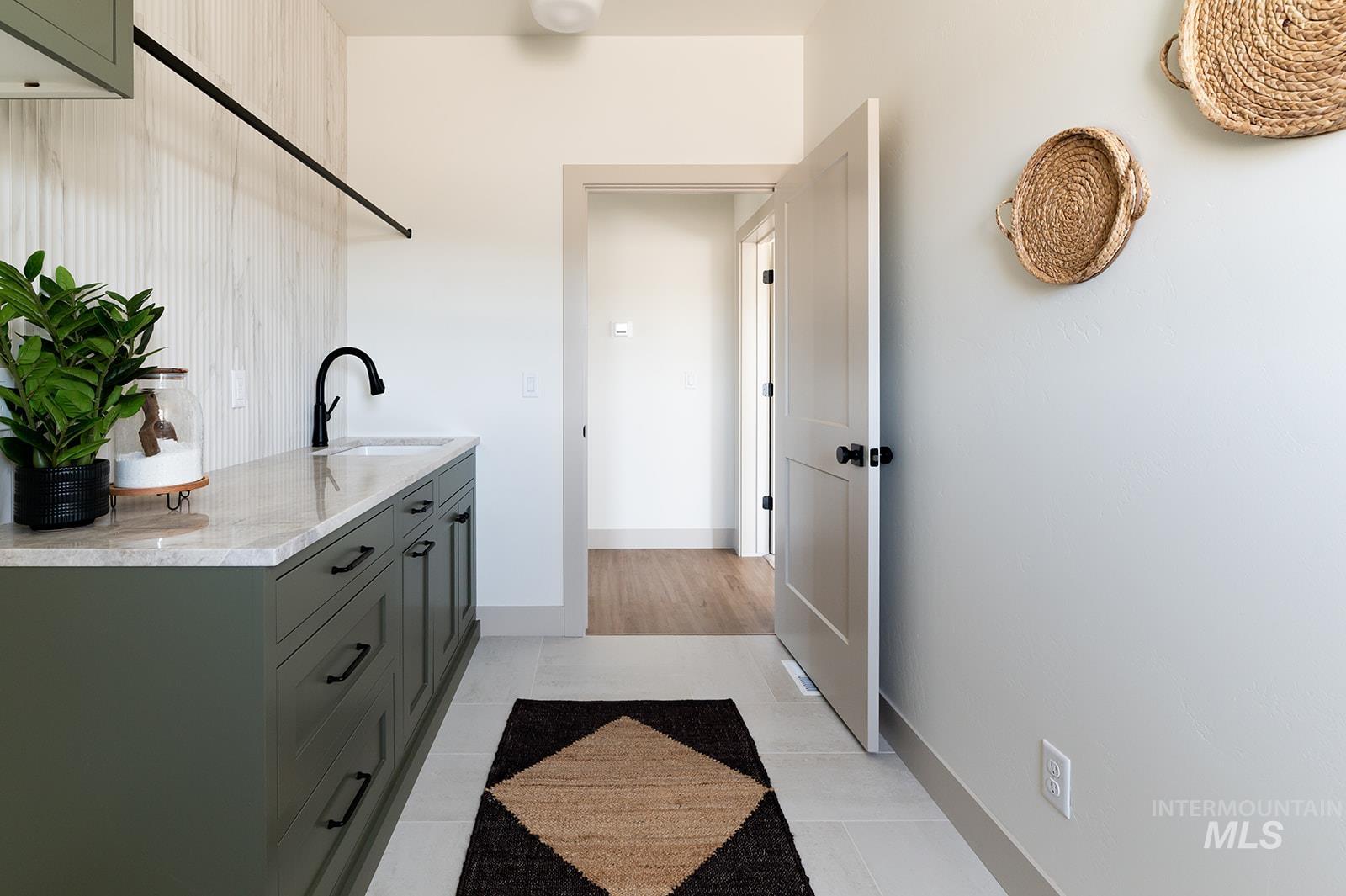 Laundry area featuring light tile patterned floors and a sink