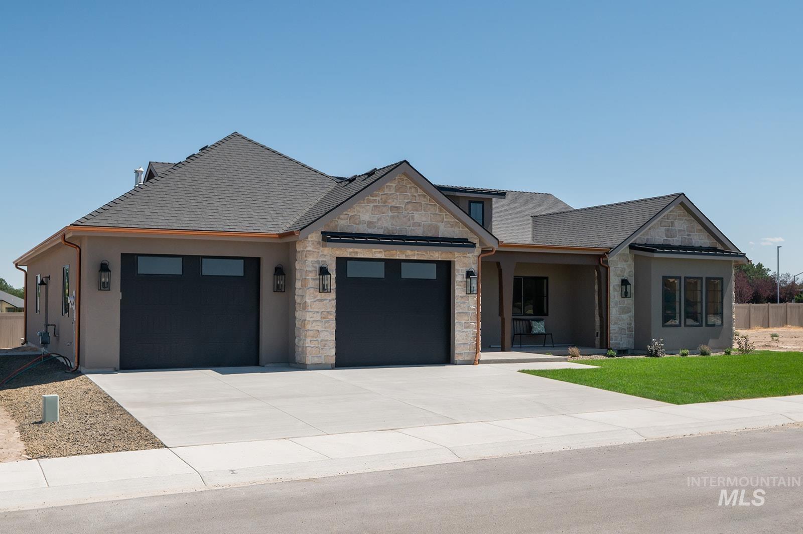 View of front of house featuring an attached garage, stucco siding, stone siding, and driveway