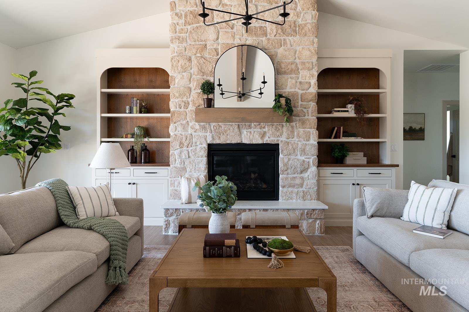 Living area with lofted ceiling, light wood-style floors, and a stone fireplace