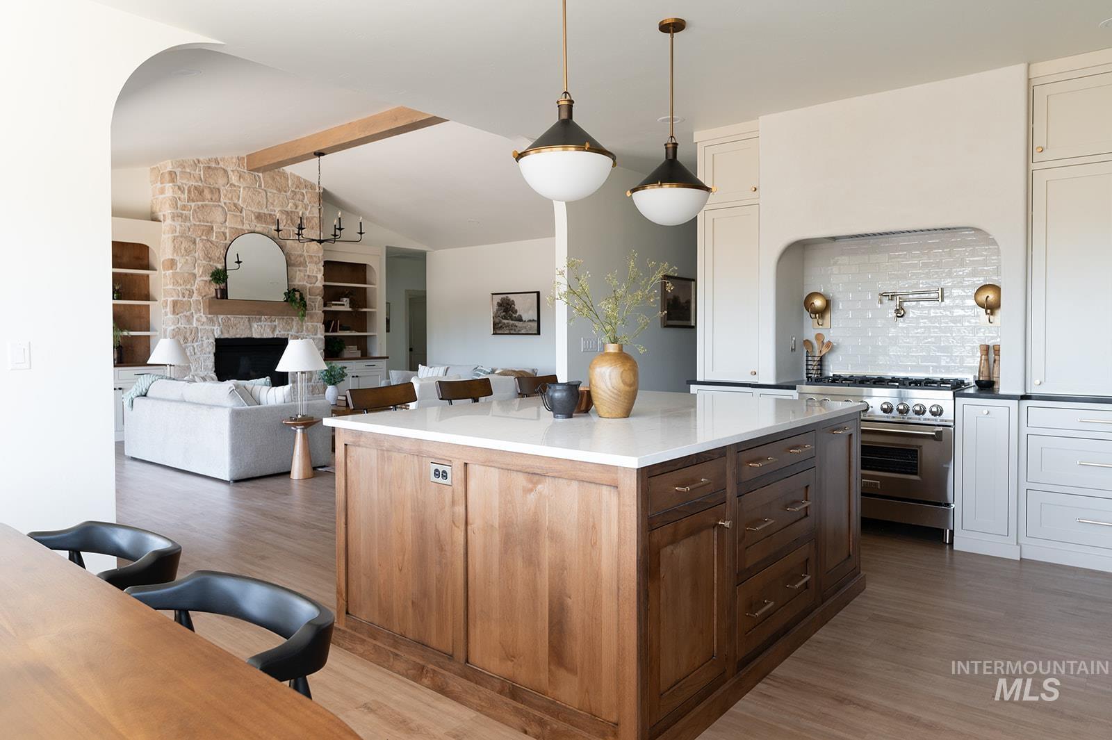 Kitchen with high end range, tasteful backsplash, wood finished floors, and white cabinetry