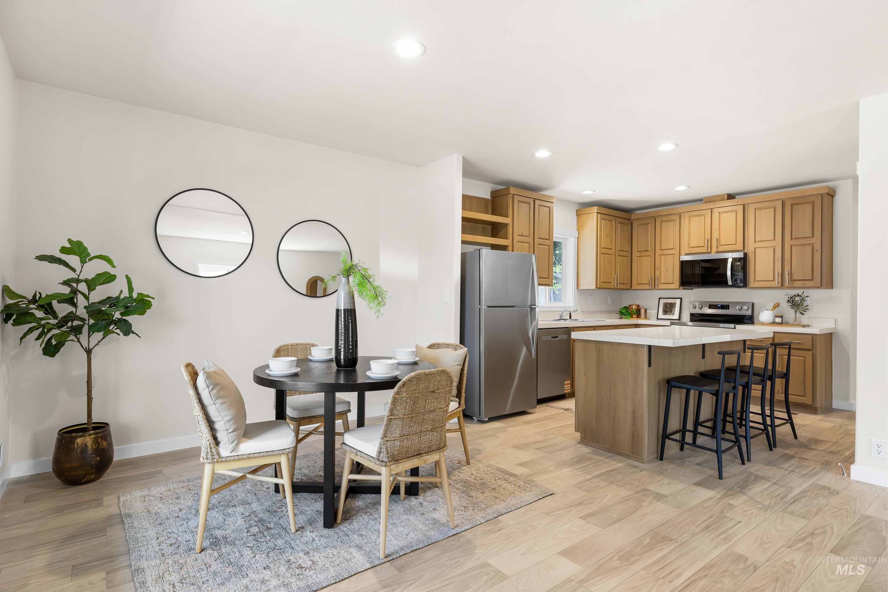 Kitchen with stainless steel appliances, open shelves, a breakfast bar, light wood finished floors, and a kitchen island