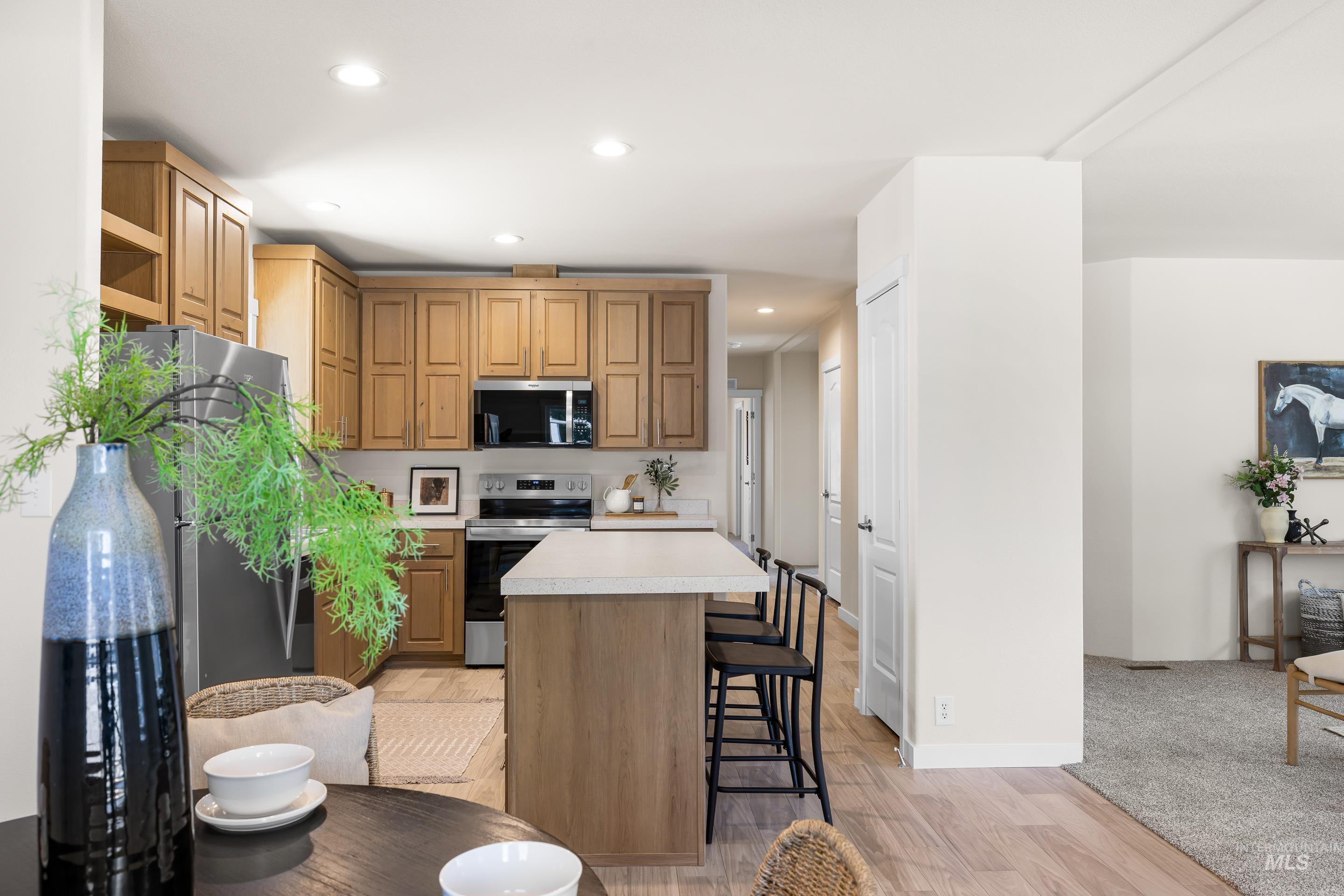 Kitchen with stainless steel appliances, a breakfast bar area, light countertops, a center island, and light wood-style flooring
