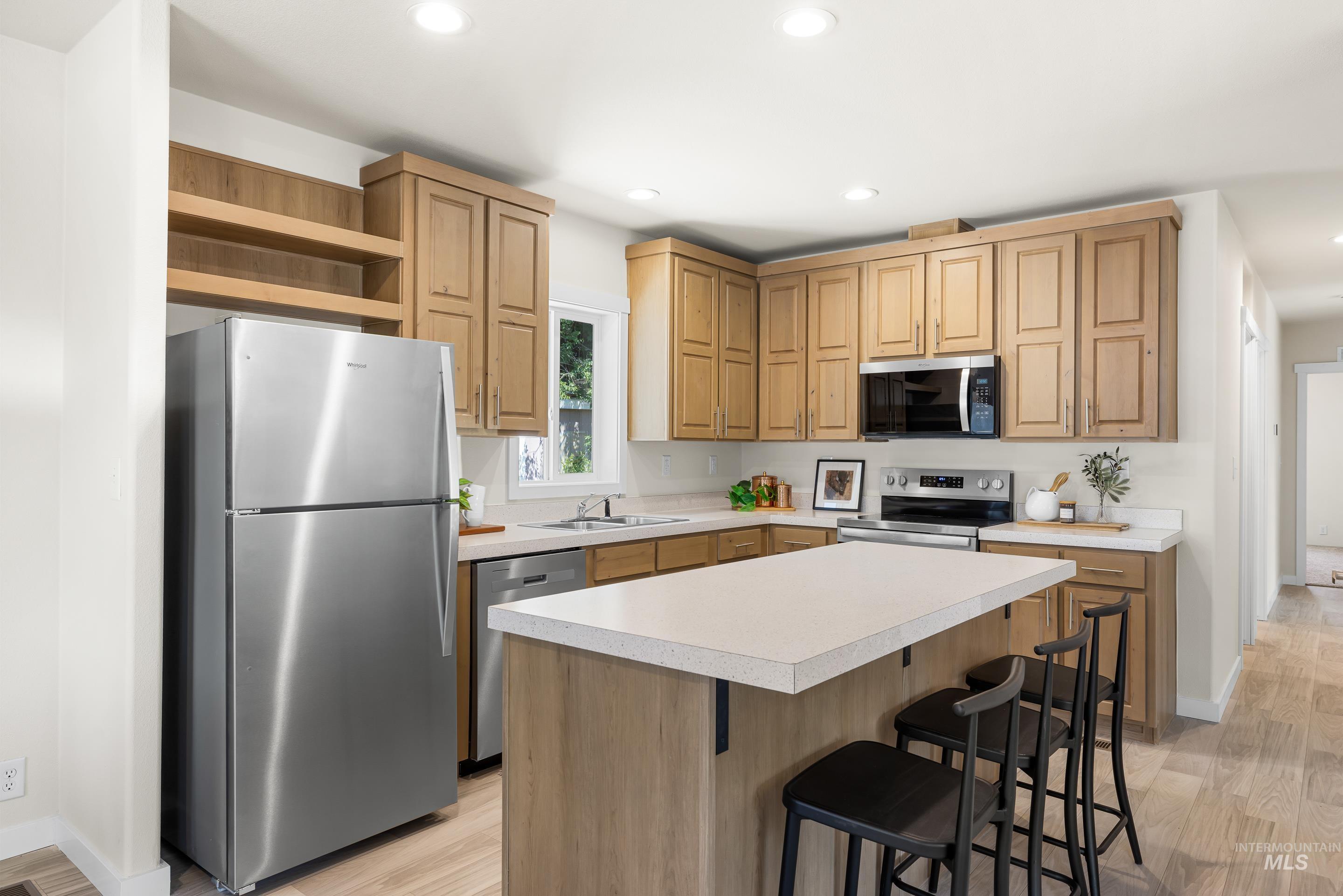 Kitchen with stainless steel appliances, open shelves, light countertops, recessed lighting, and light wood-type flooring