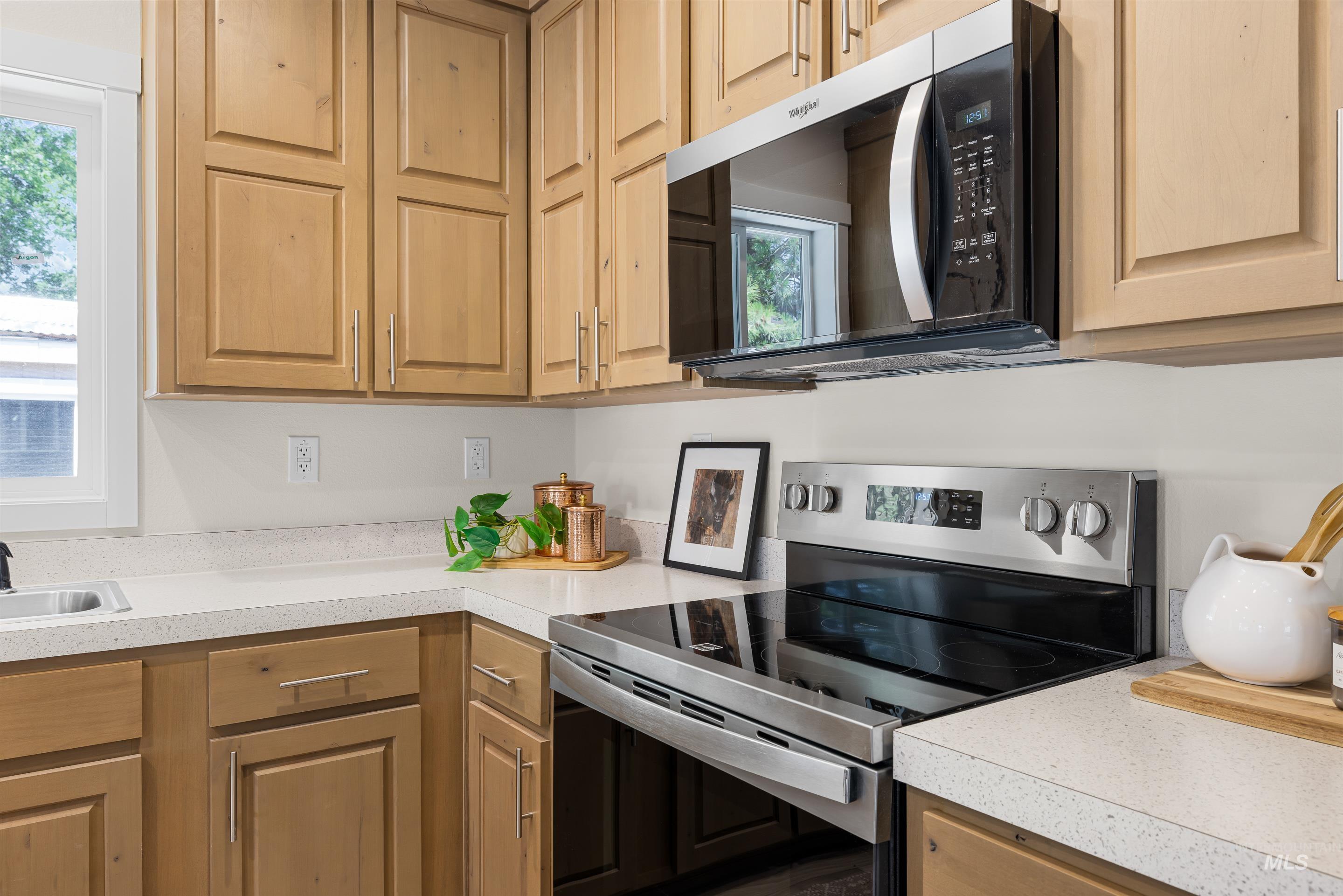 Kitchen featuring stainless steel range with electric cooktop, healthy amount of natural light, light countertops, and light brown cabinets