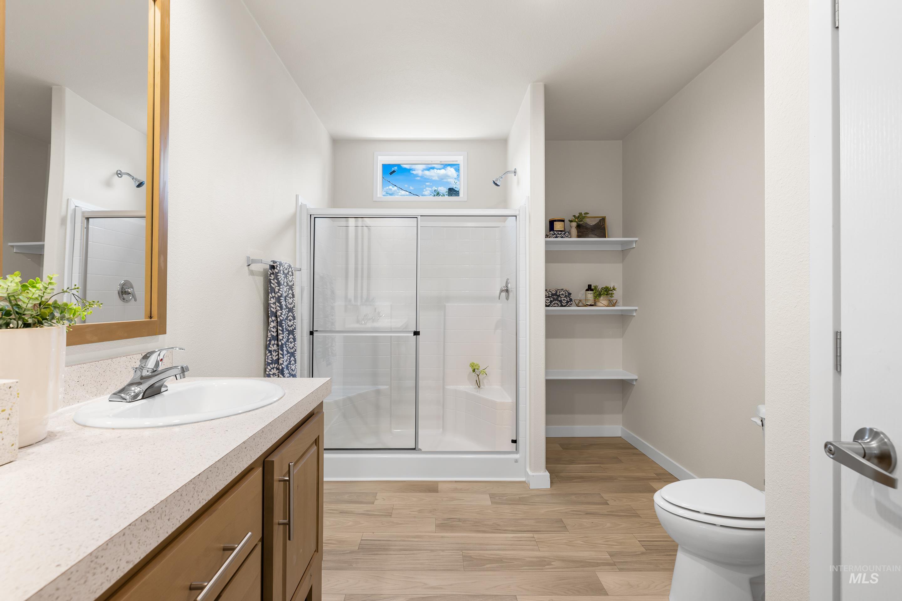 Full bath featuring wood finished floors, vanity, and a shower stall