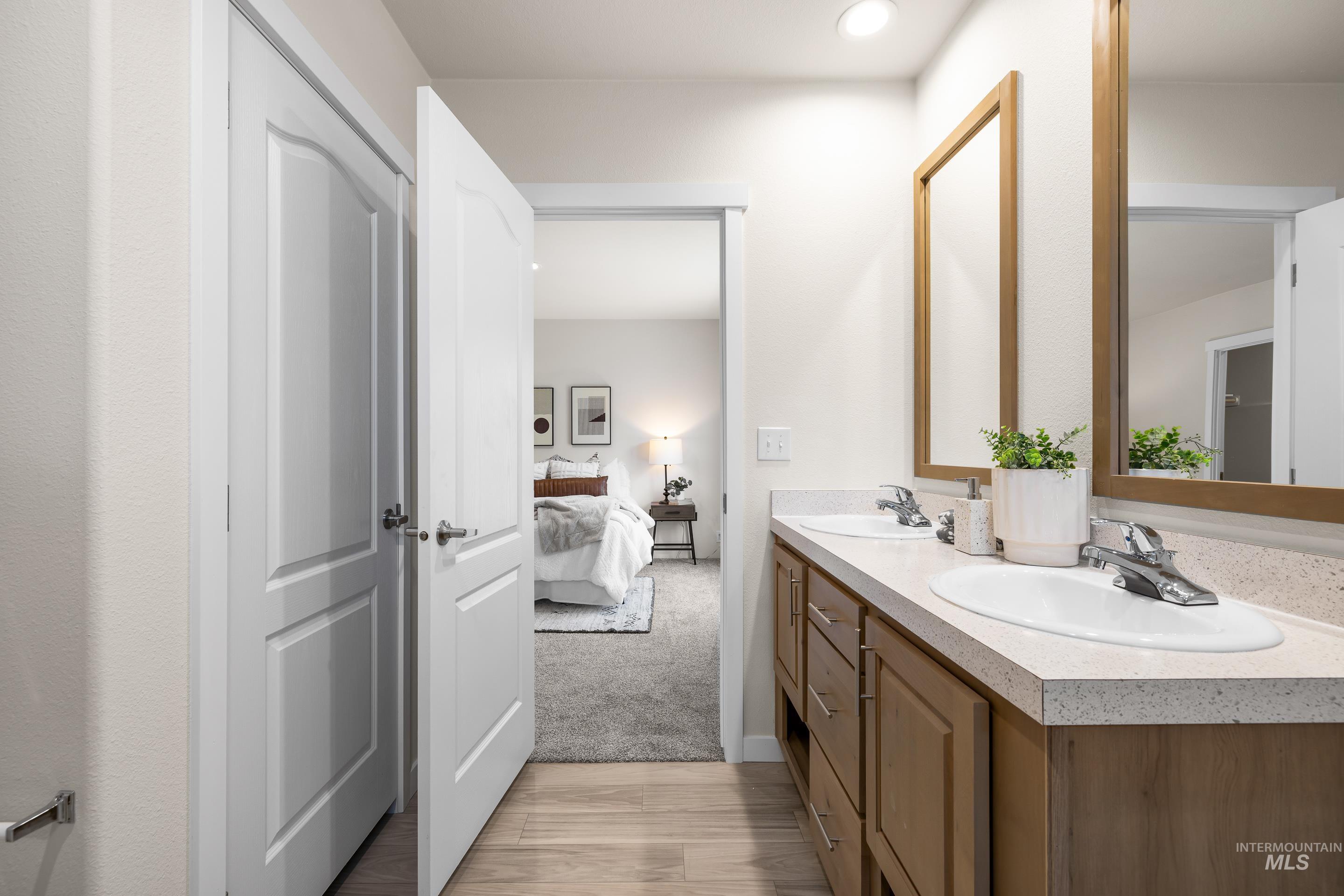 Full bathroom with connected bathroom, double vanity, wood finished floors, and recessed lighting