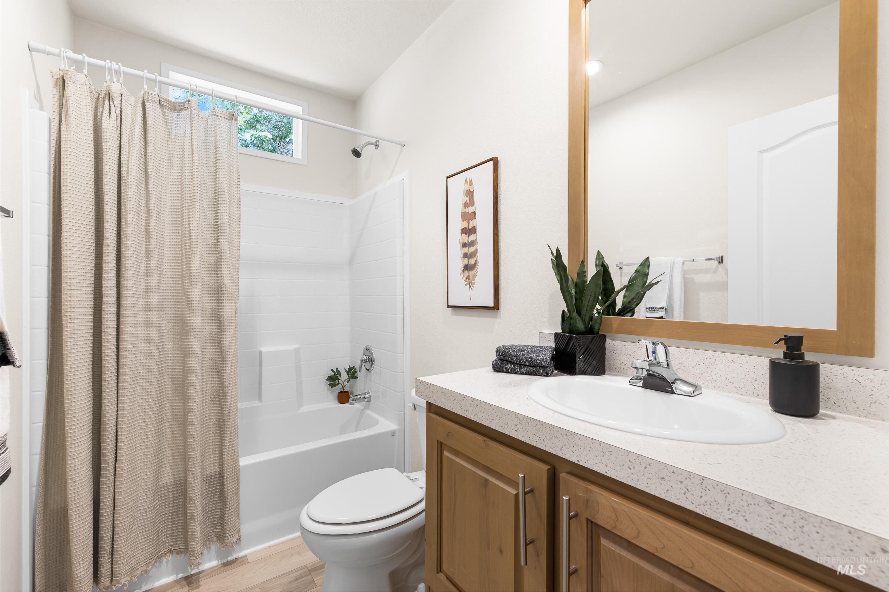 Full bath featuring vanity, shower / bathtub combination with curtain, and wood finished floors