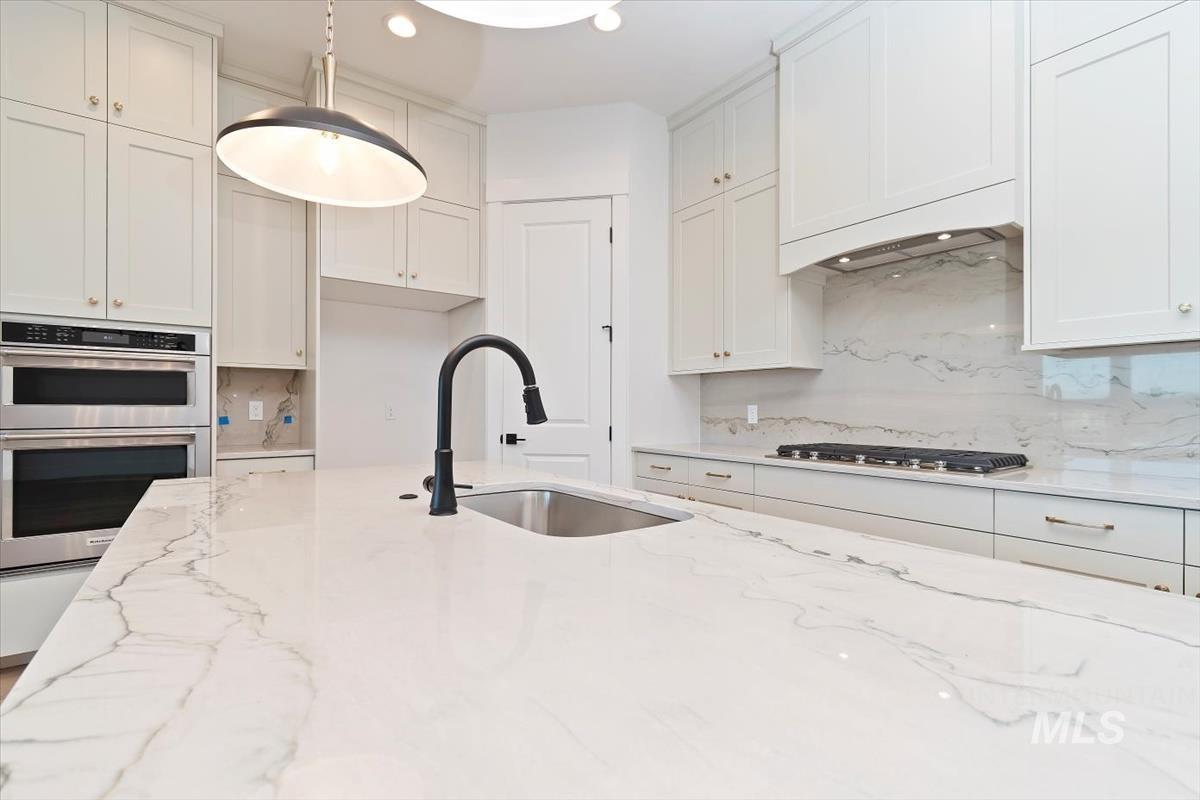 Kitchen featuring light stone countertops, stainless steel appliances, white cabinets, tasteful backsplash, and recessed lighting