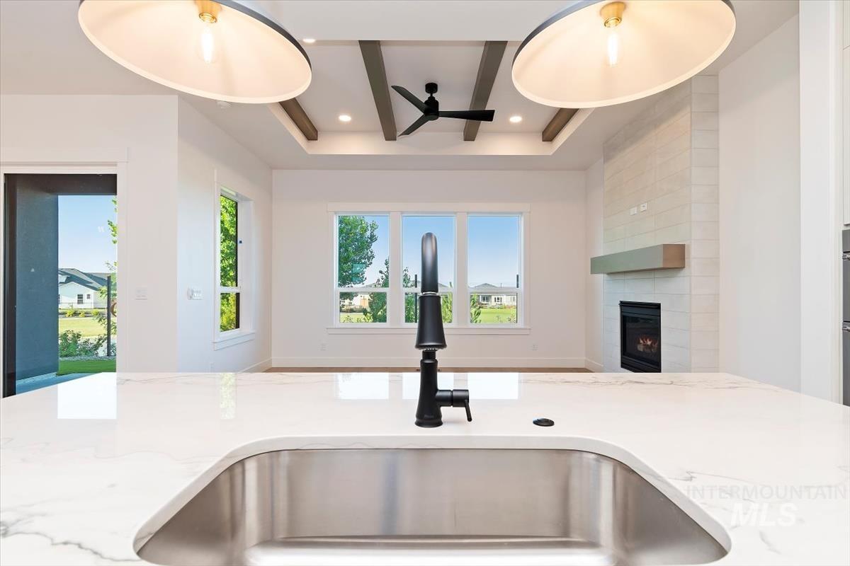Kitchen featuring light stone countertops, a tiled fireplace, and ceiling fan