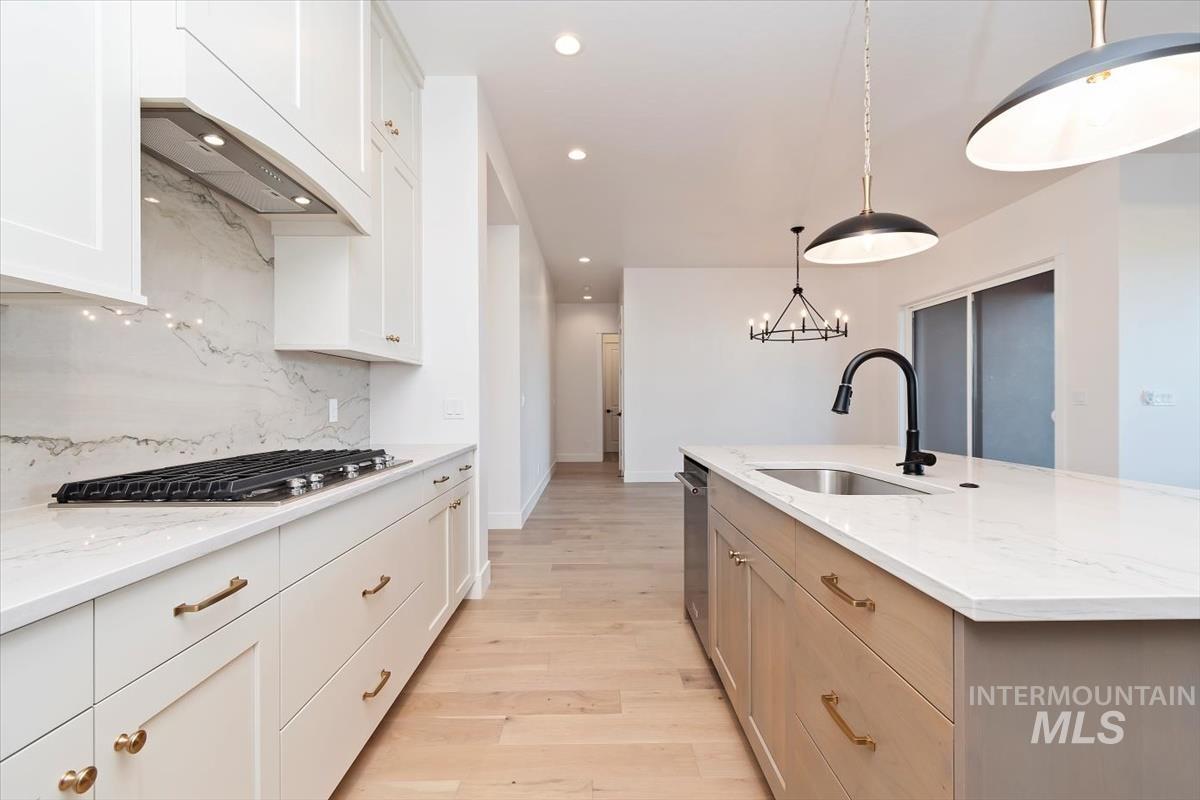 Kitchen featuring white cabinets, light wood finished floors, light stone counters, and recessed lighting