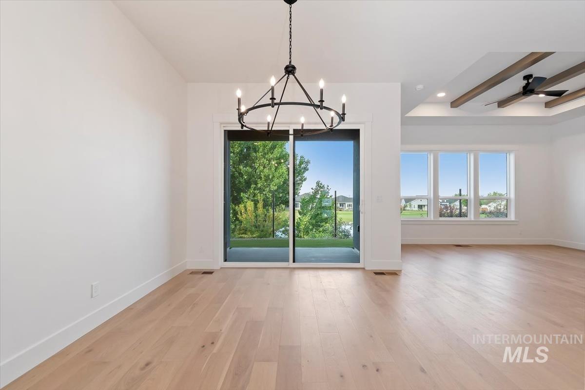 Unfurnished dining area featuring plenty of natural light, light wood-style flooring, a chandelier, beamed ceiling, and recessed lighting