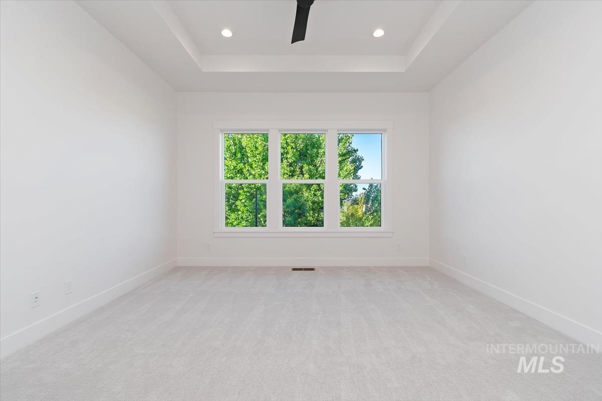 Unfurnished room with a tray ceiling, light carpet, ceiling fan, and recessed lighting